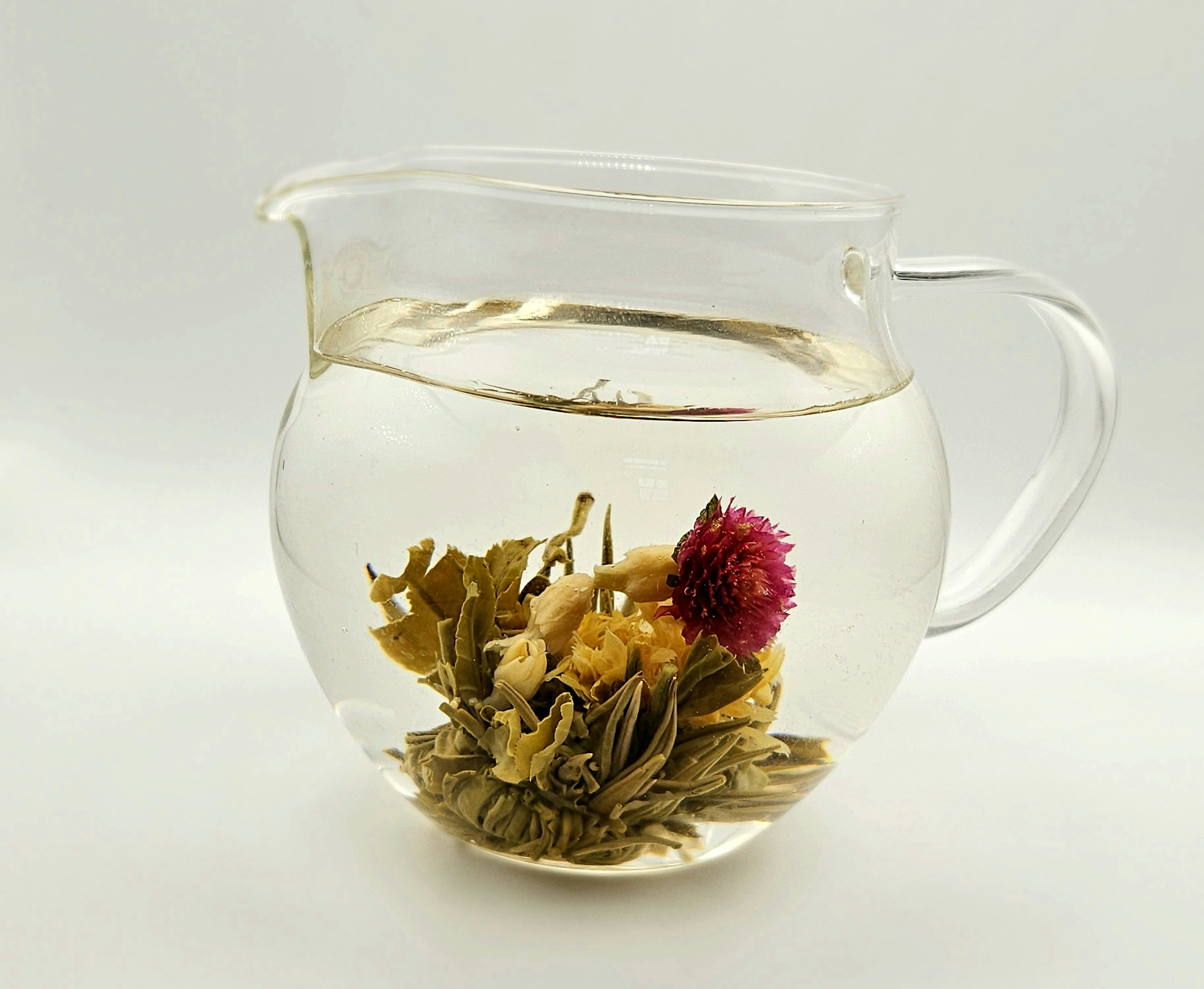 Tetera transparente con té de flores en flor y agua cristalina