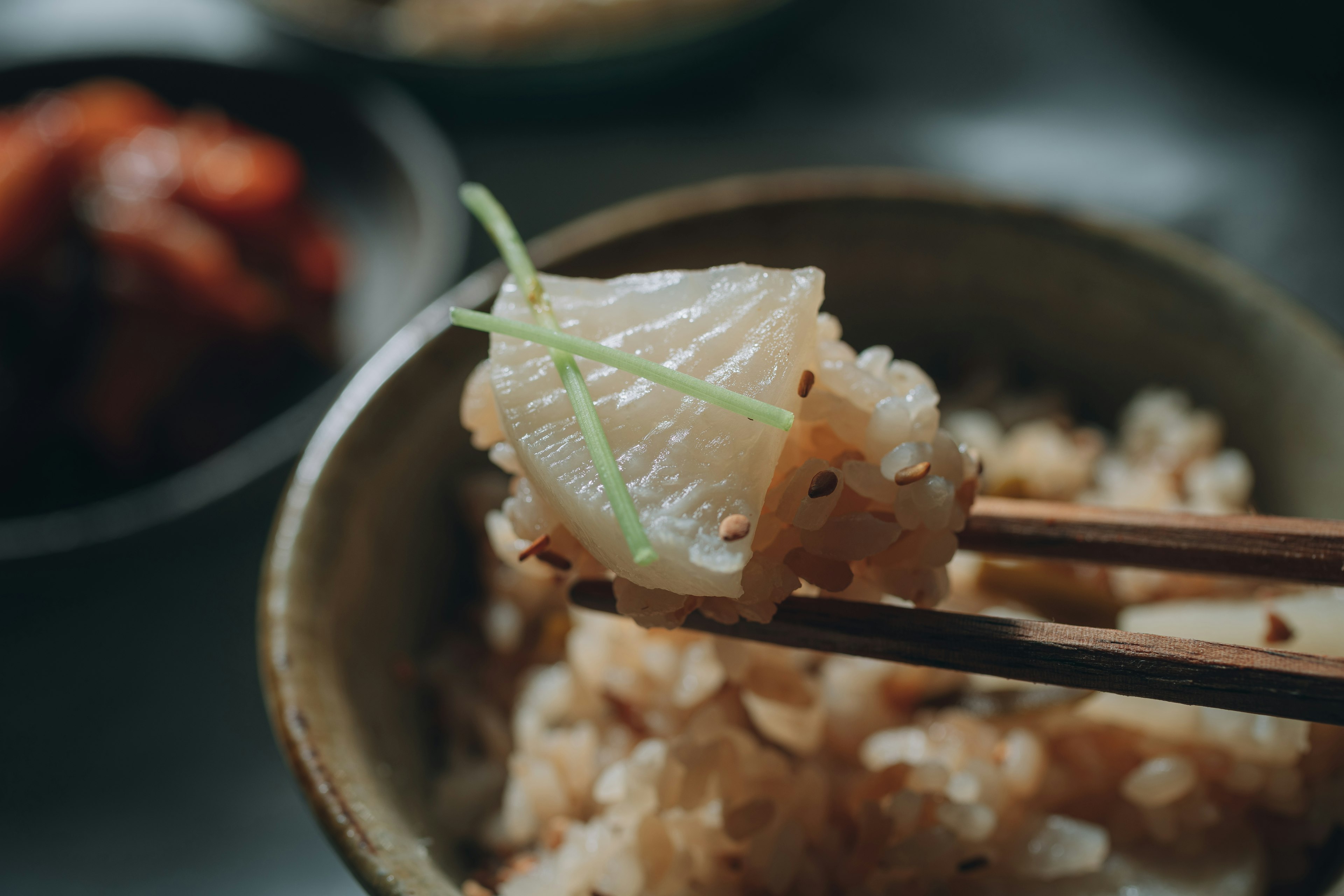 A bite of rice with herbs held by chopsticks