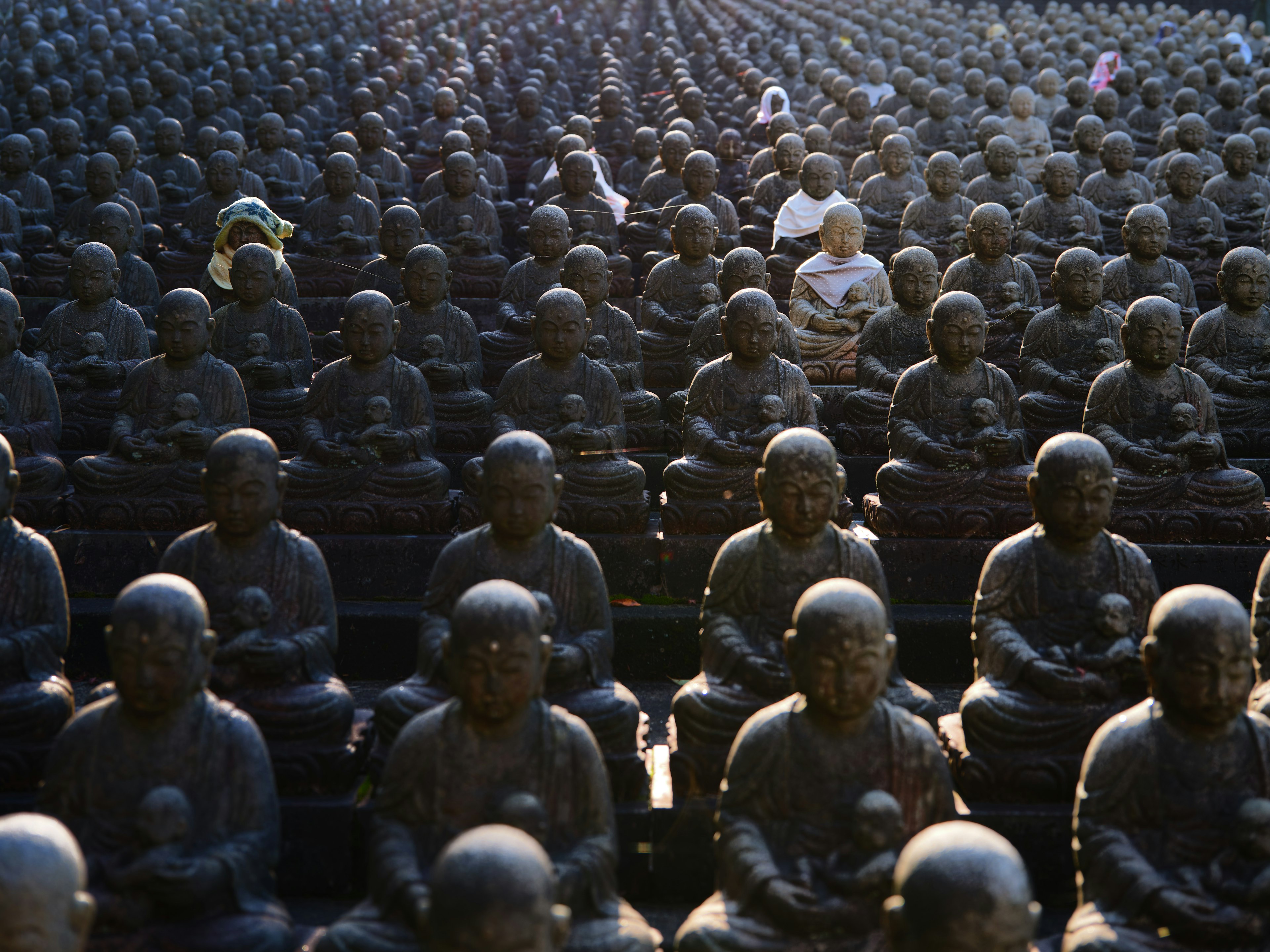 Eine Szene mit zahlreichen sitzenden Buddha-Statuen und einer Person dazwischen