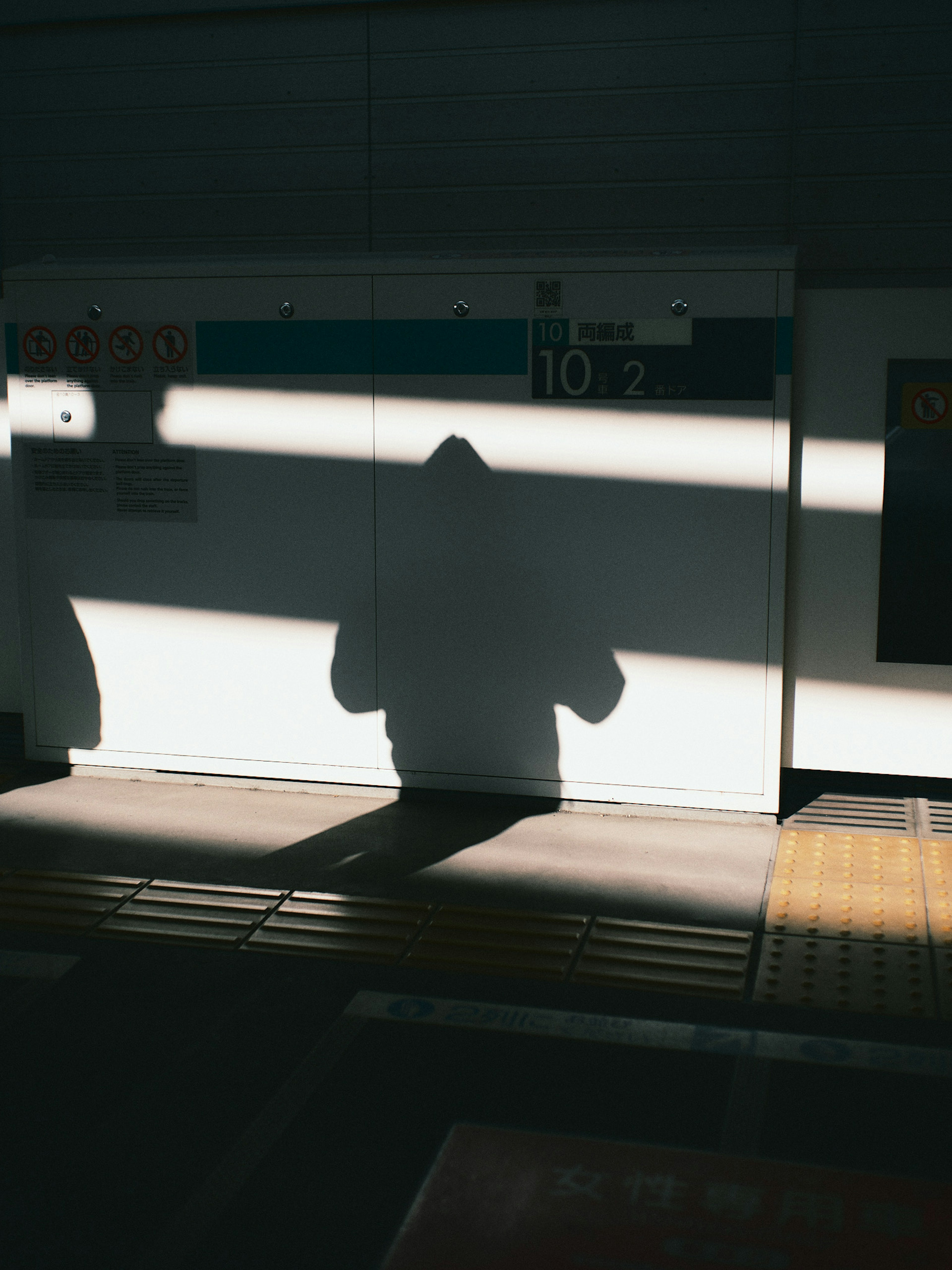 Schatten einer Person auf einem Bahnsteig mit kontrastierendem Licht