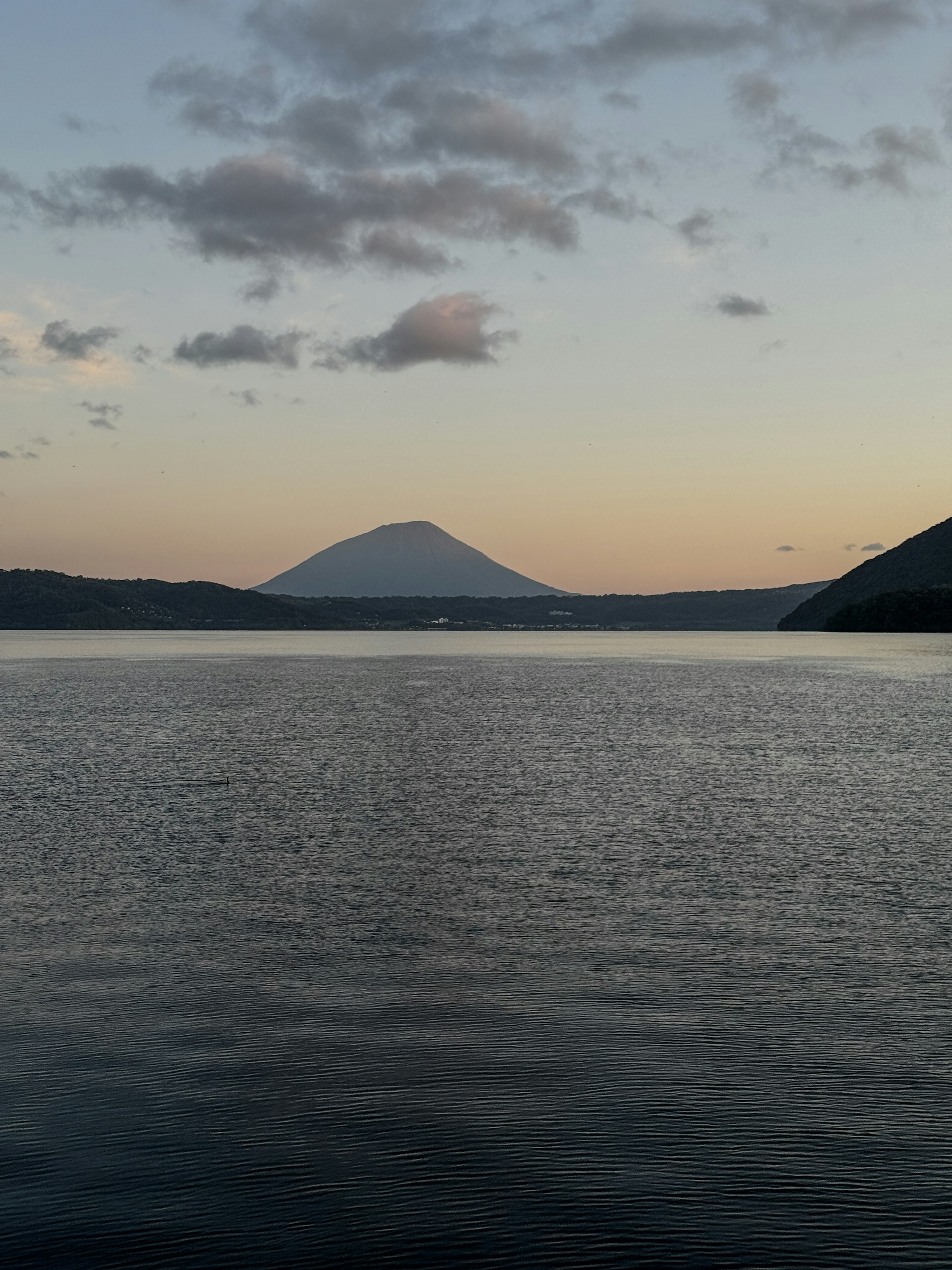 Pemandangan tenang danau dan gunung saat senja dengan permukaan air tenang