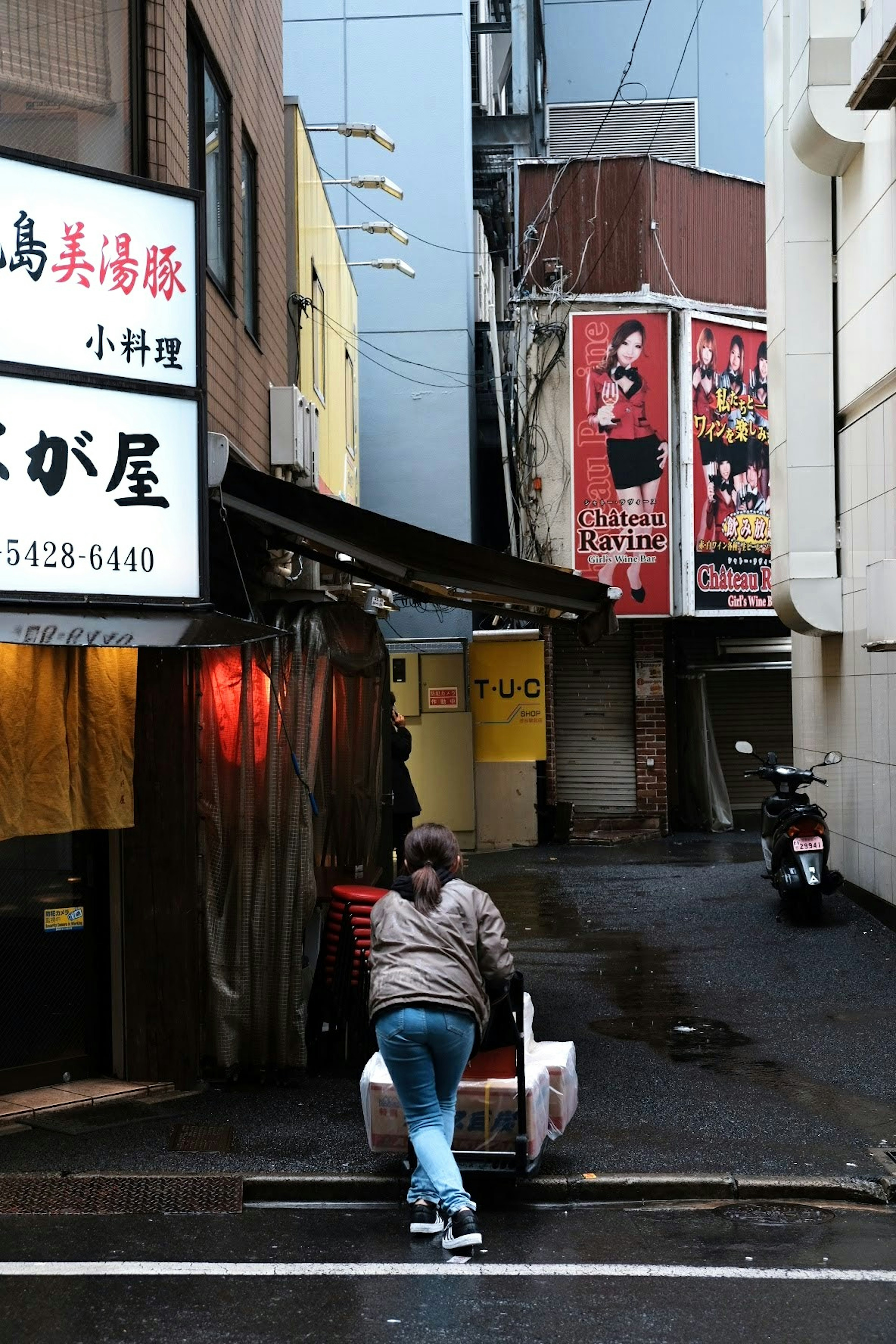 在狭窄巷道中拉着手推车的人和餐馆招牌