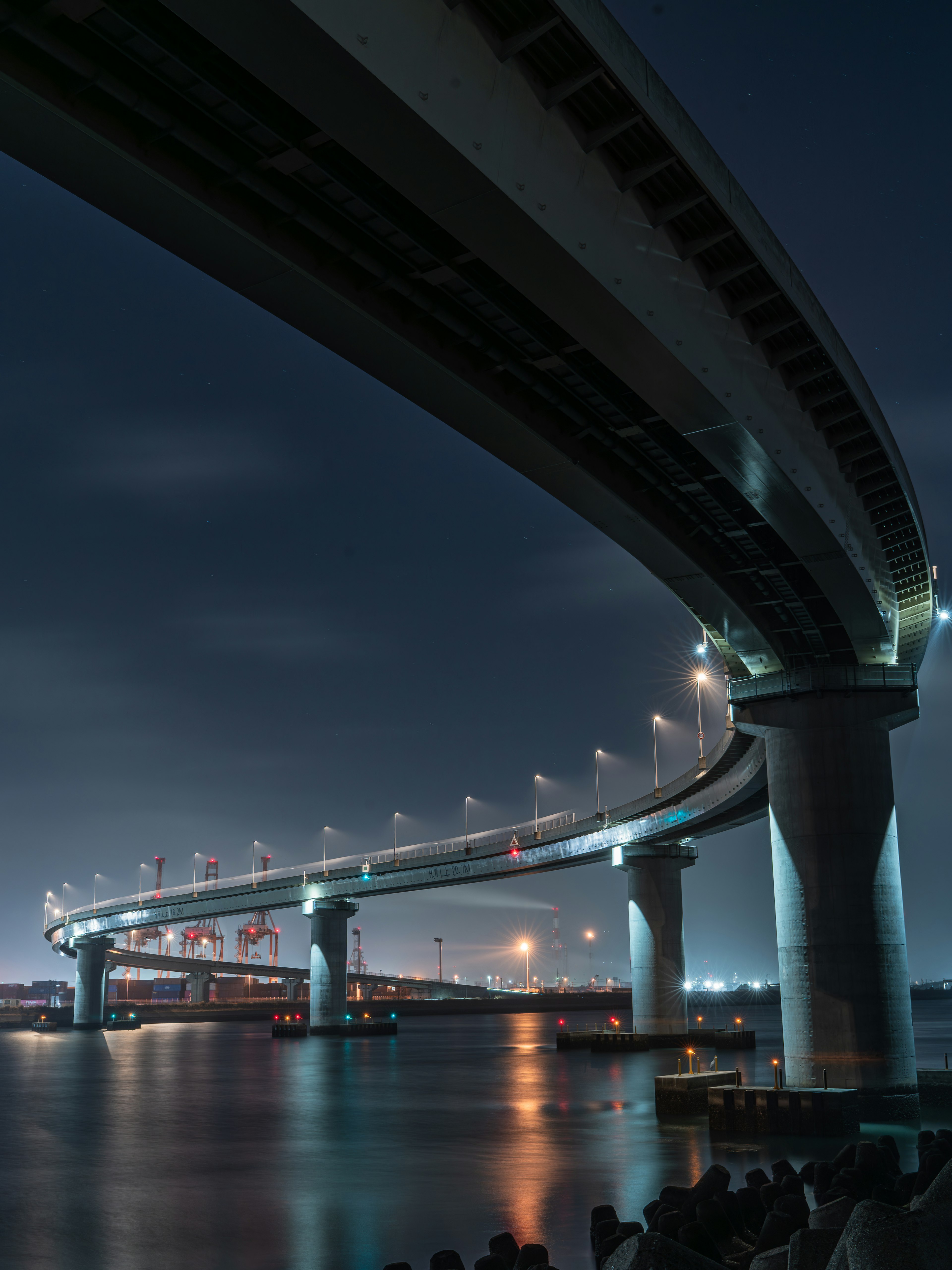 Pemandangan dari bawah jembatan tinggi yang diterangi indah di malam hari di sebuah kota