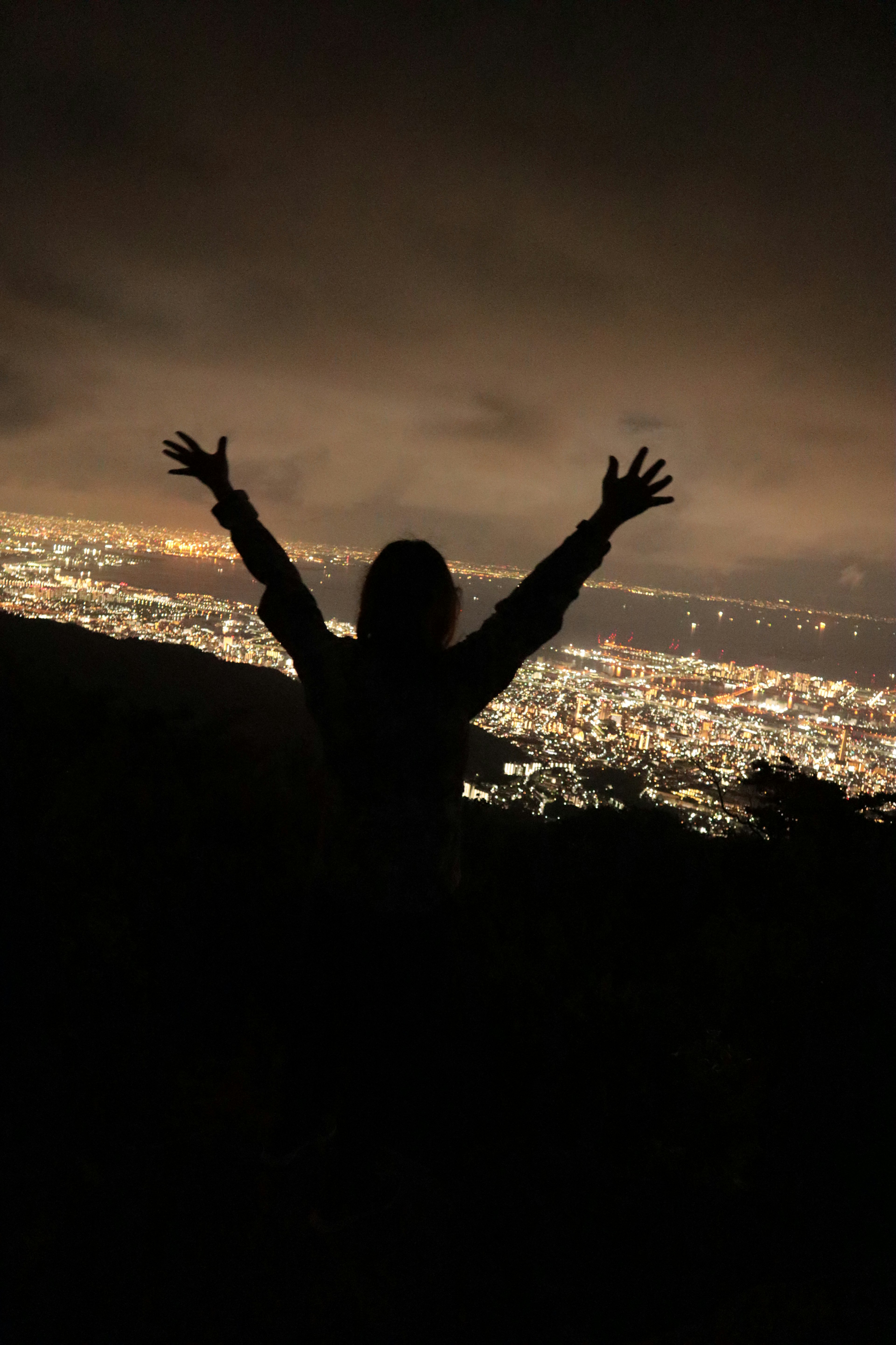 Silhouette mit erhobenen Armen vor einer nächtlichen Stadtansicht