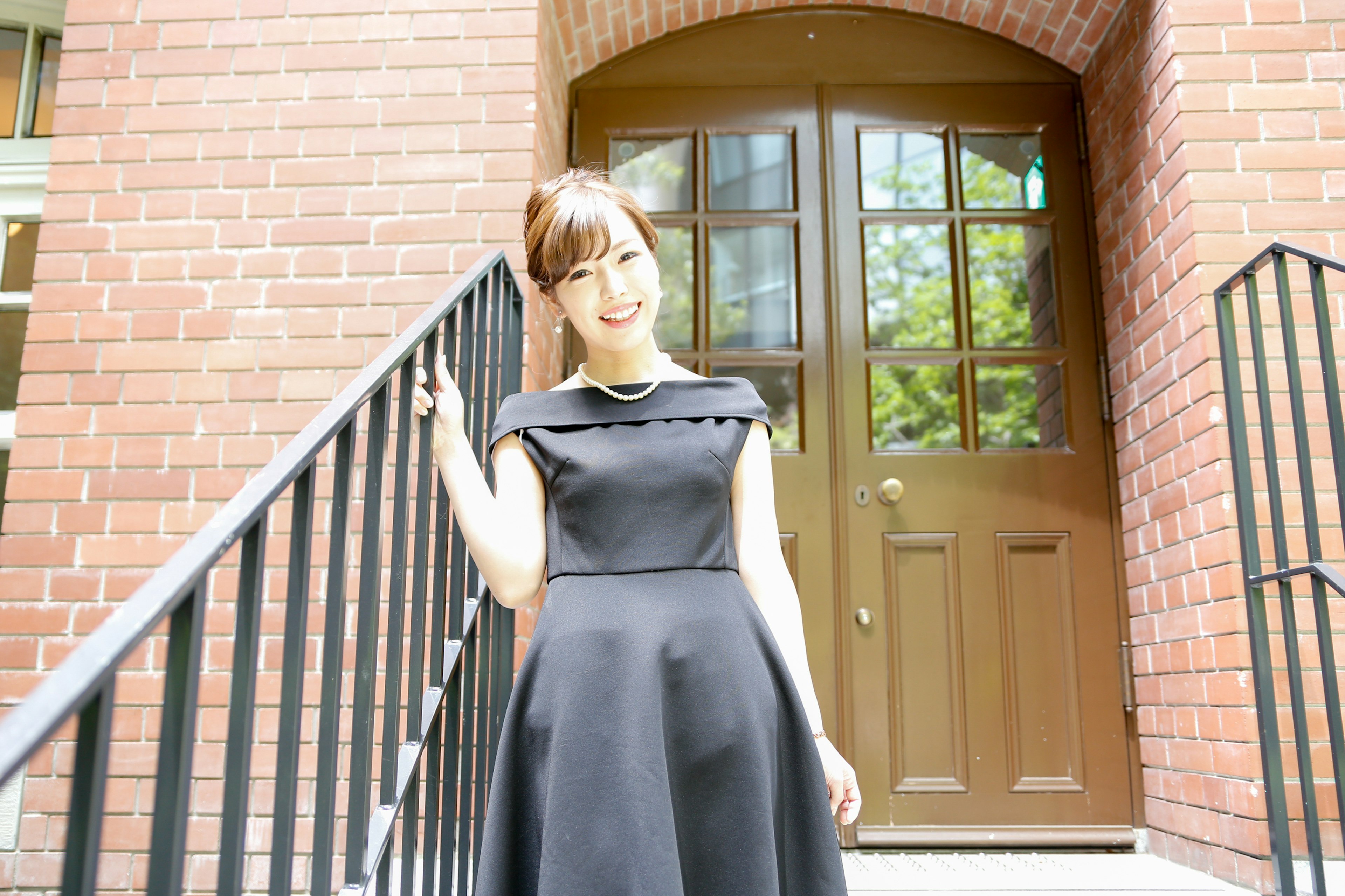 A woman in a black dress smiling on the stairs