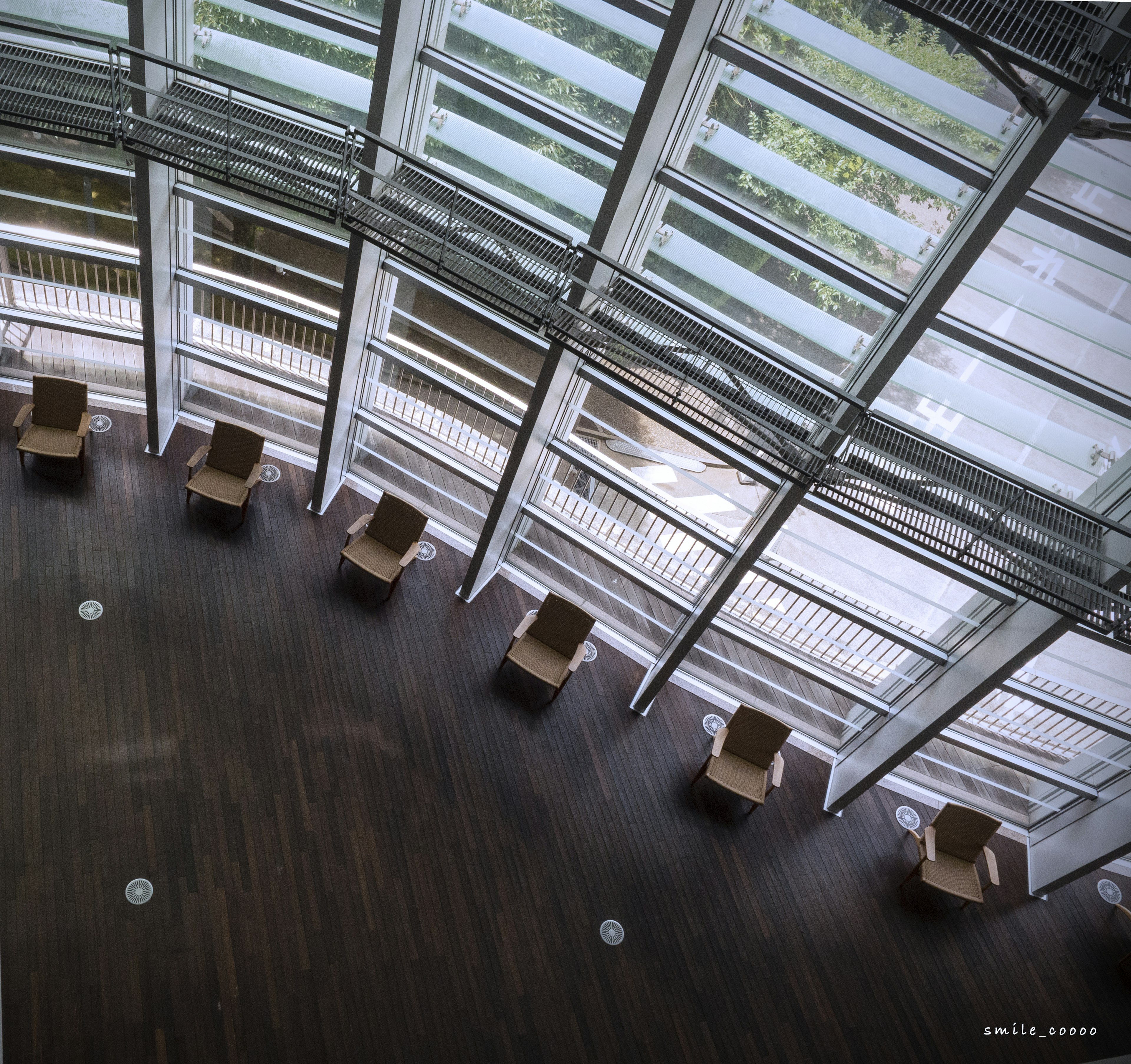 Modern indoor space with large windows featuring a circular arrangement of wooden chairs