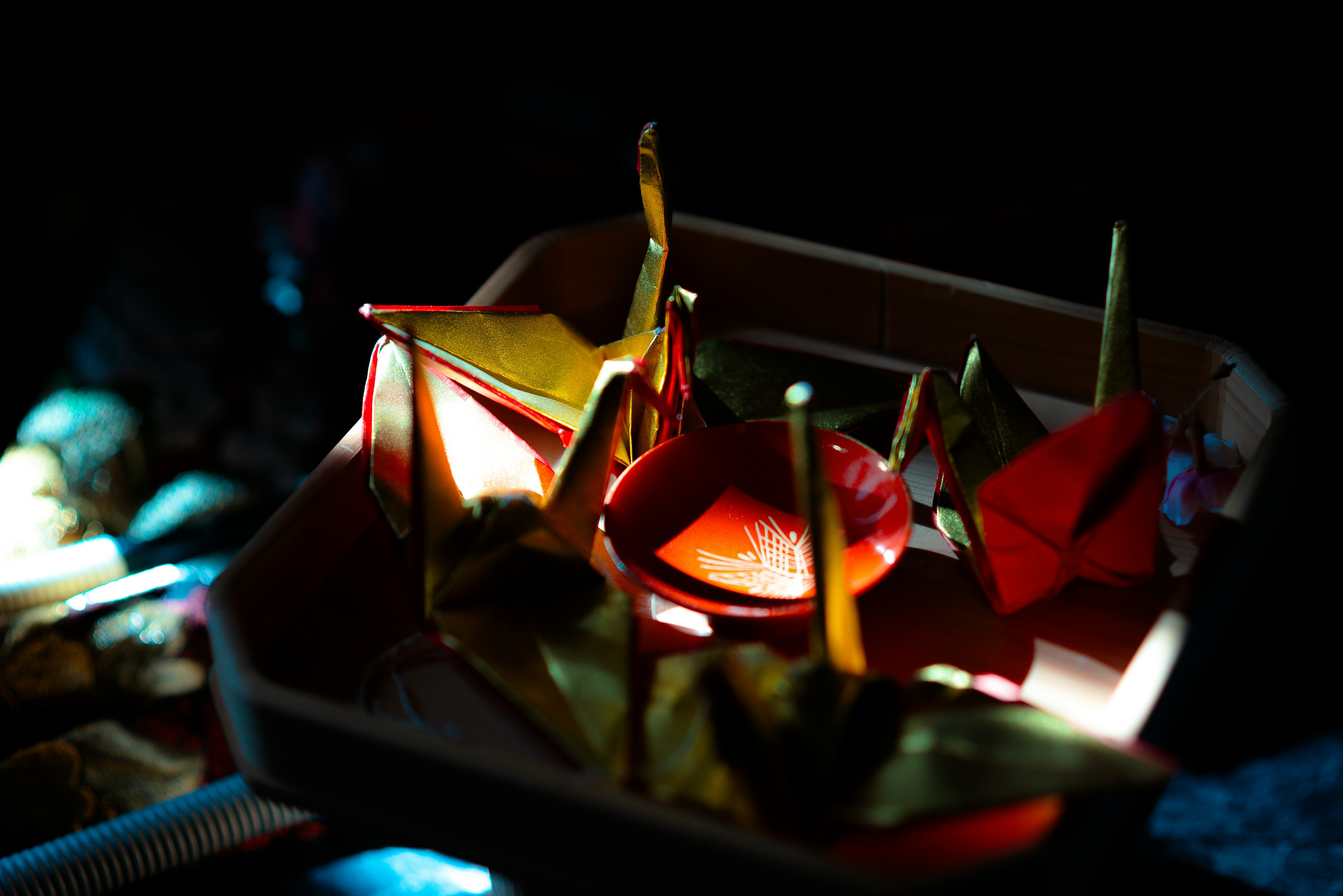 Origami cranes and boats illuminated against a dark background