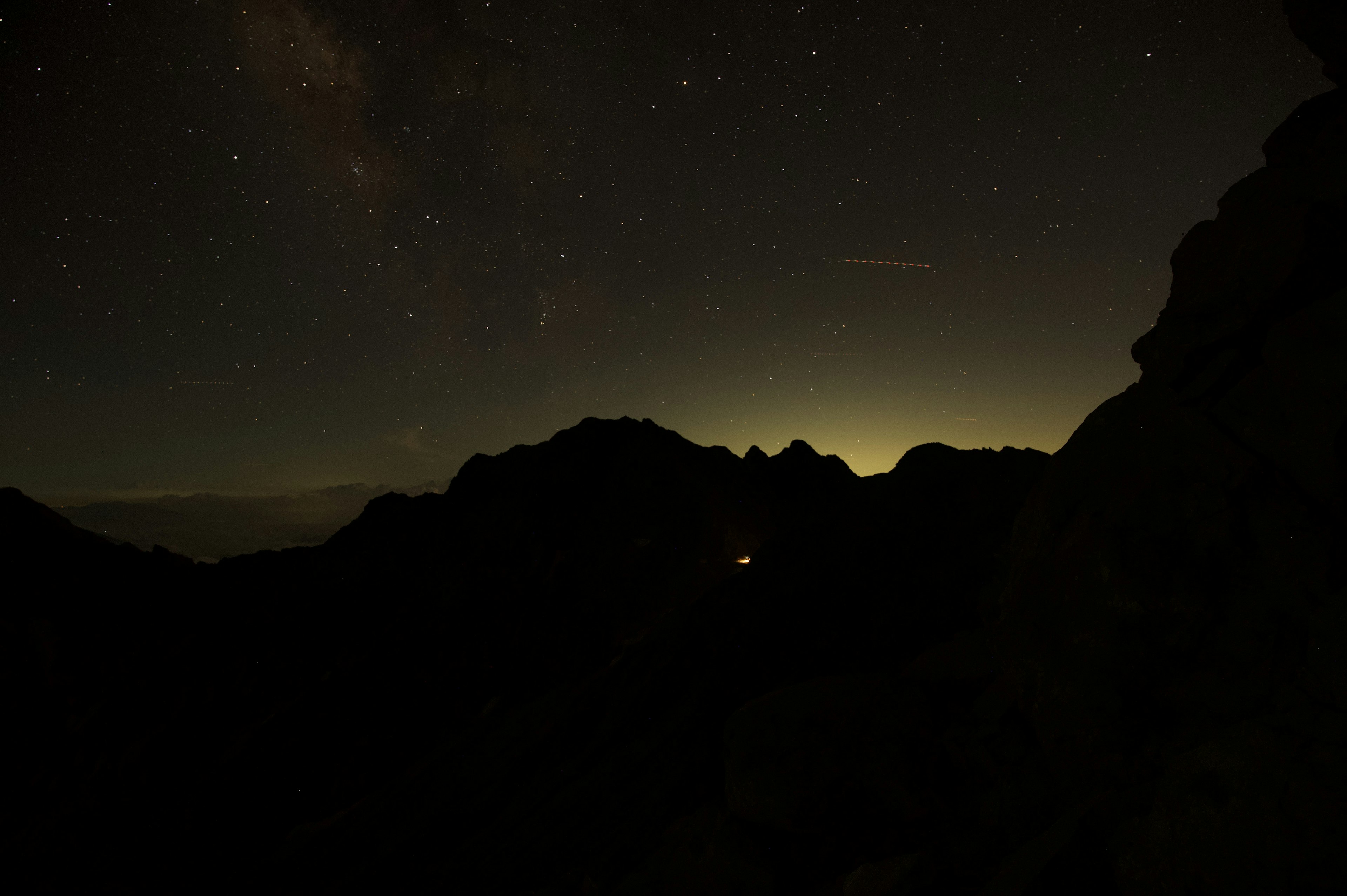 暗い山々のシルエットと星空の夜景