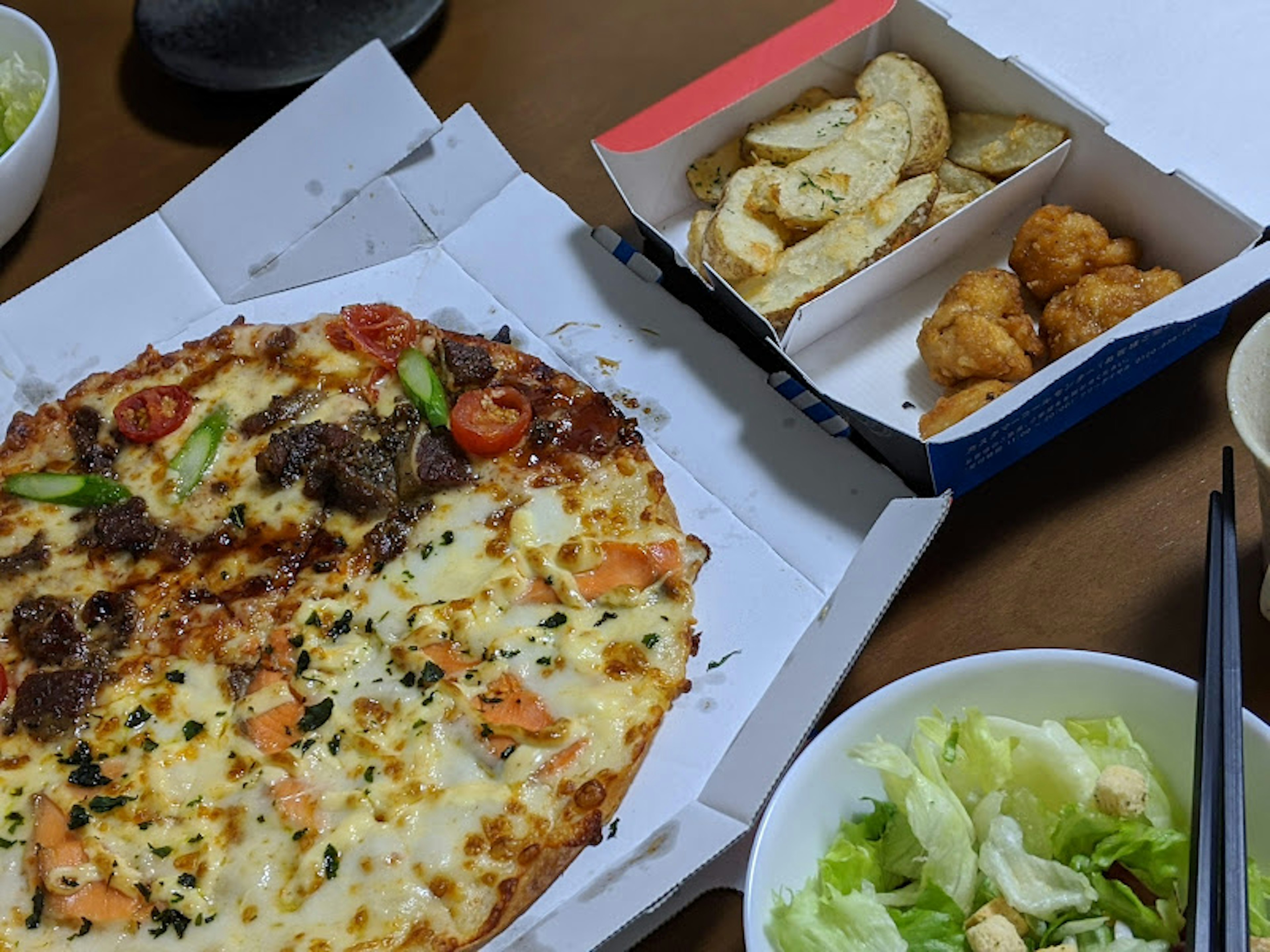 Une table avec une pizza, une salade et des plats frits