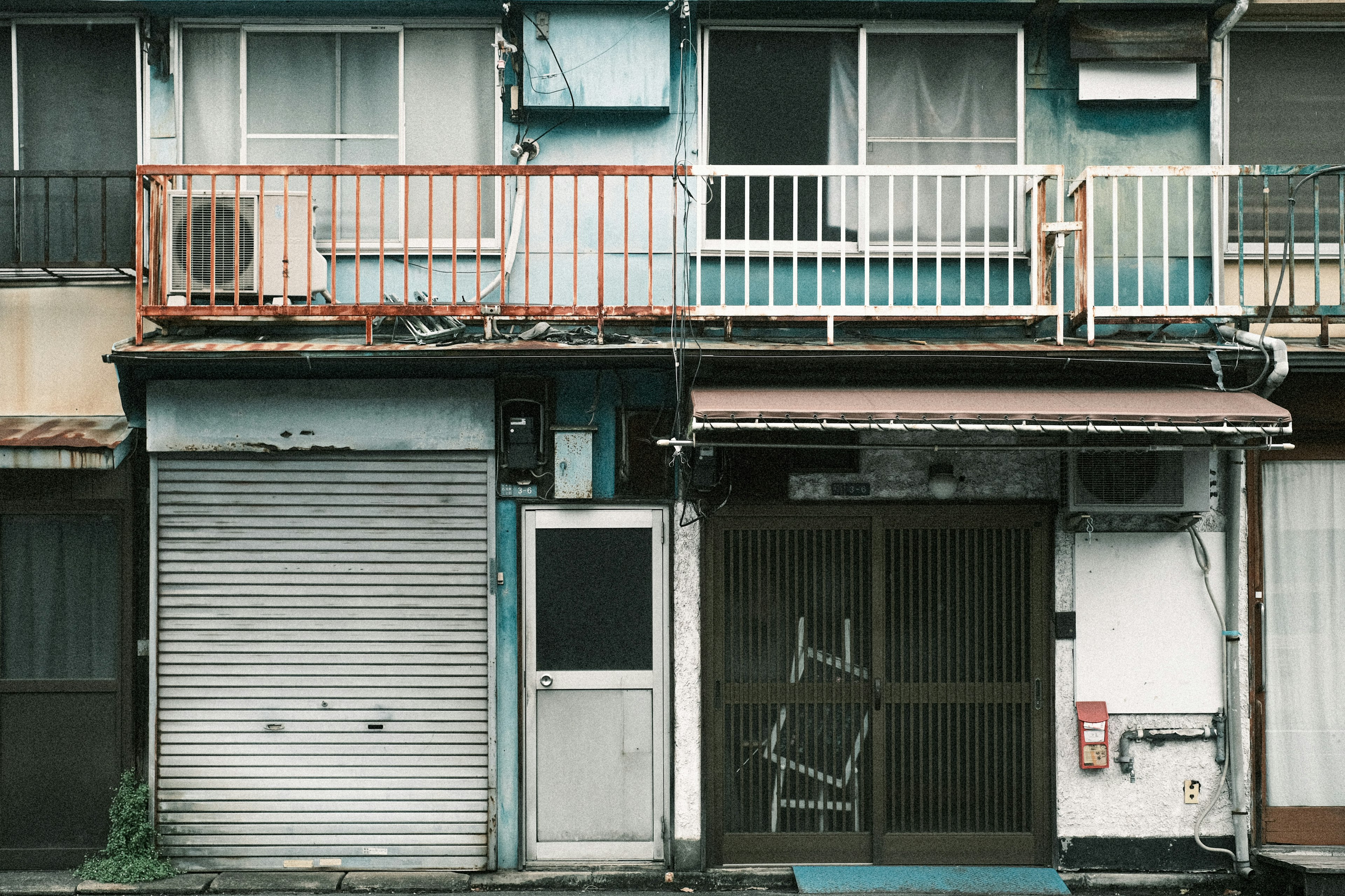 Exterior de un viejo edificio de apartamentos con persianas cerradas y un balcón visible