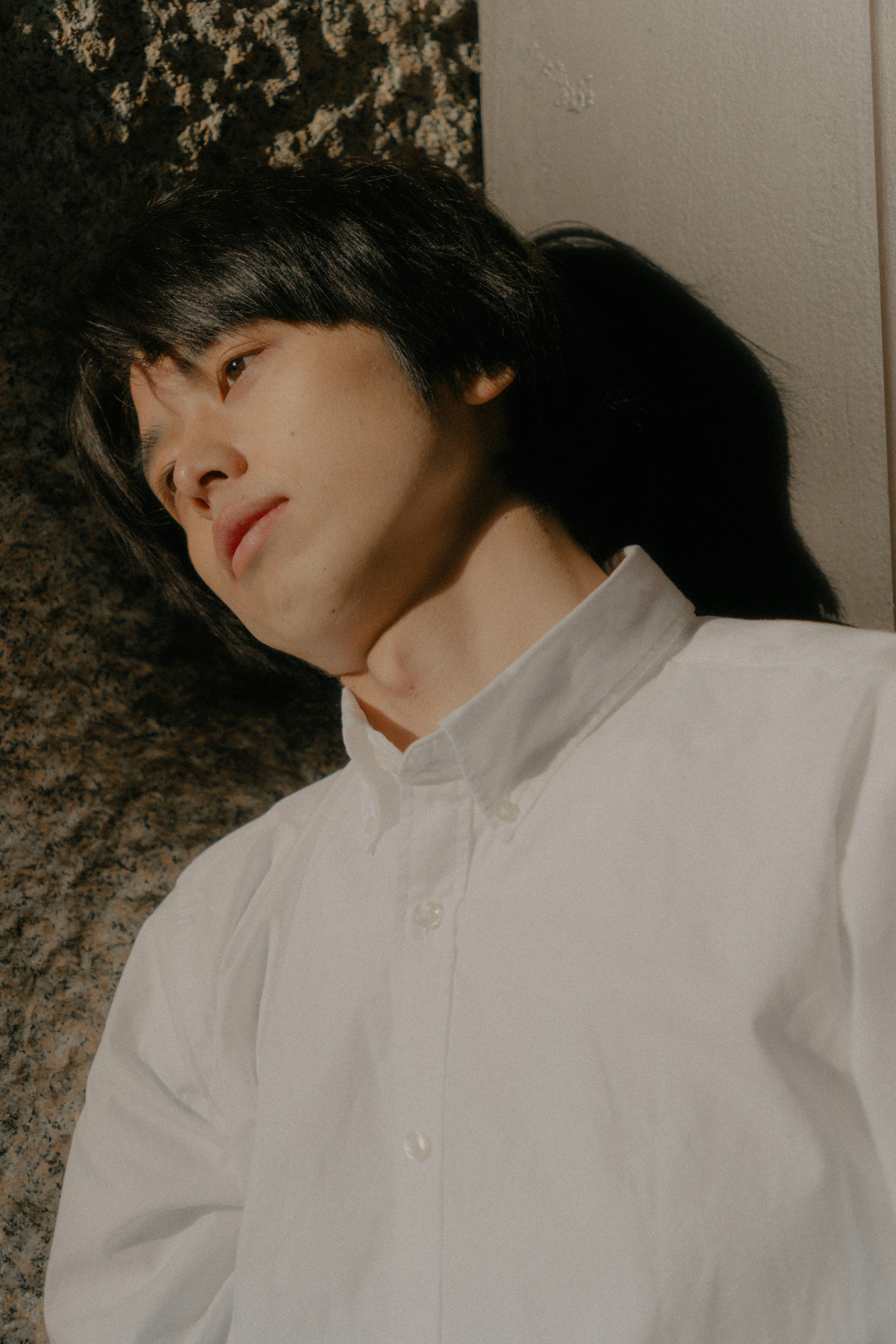 A man in a white shirt lying down with a serene expression