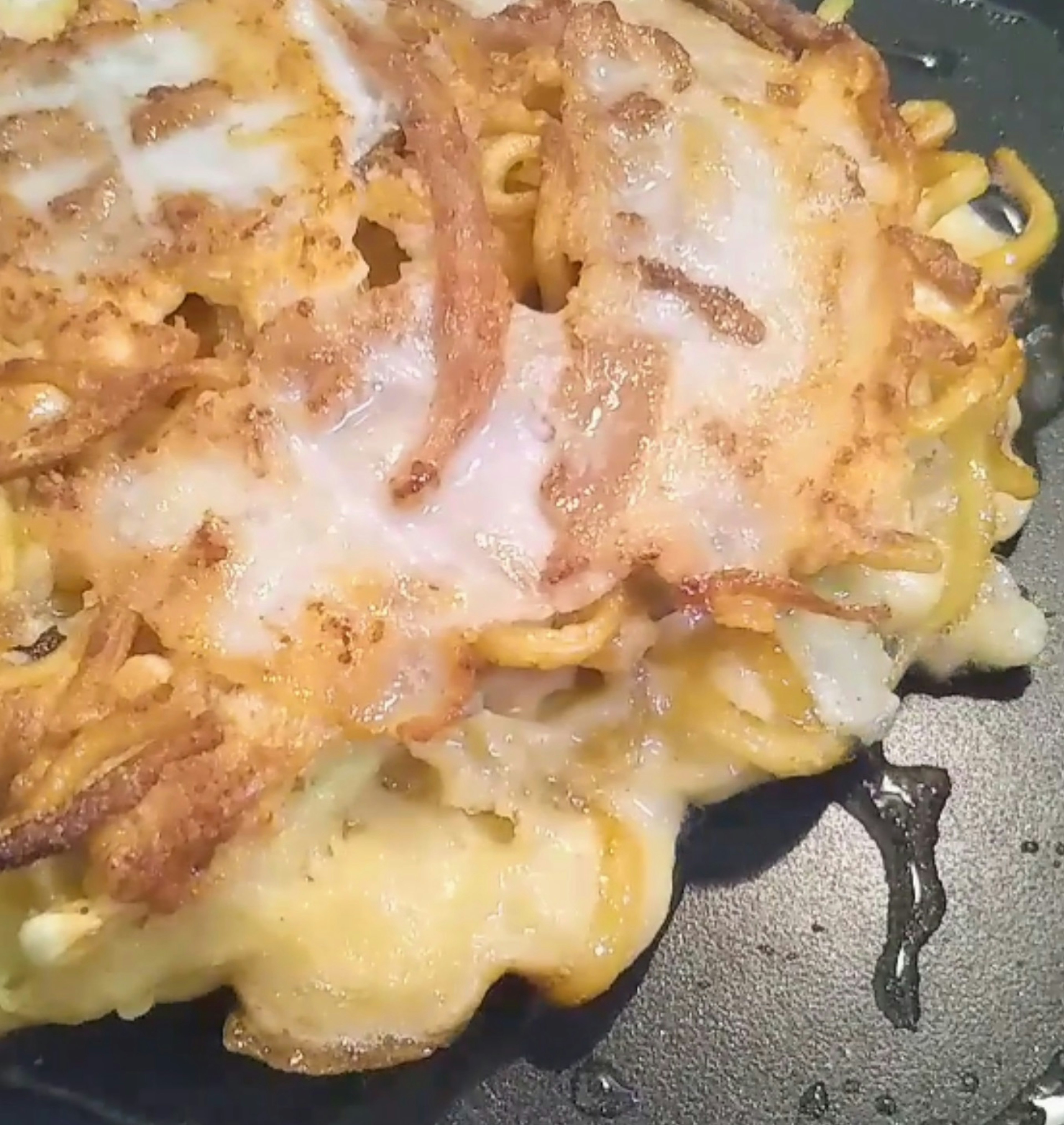 Fried noodle and potato pancake resting in a frying pan