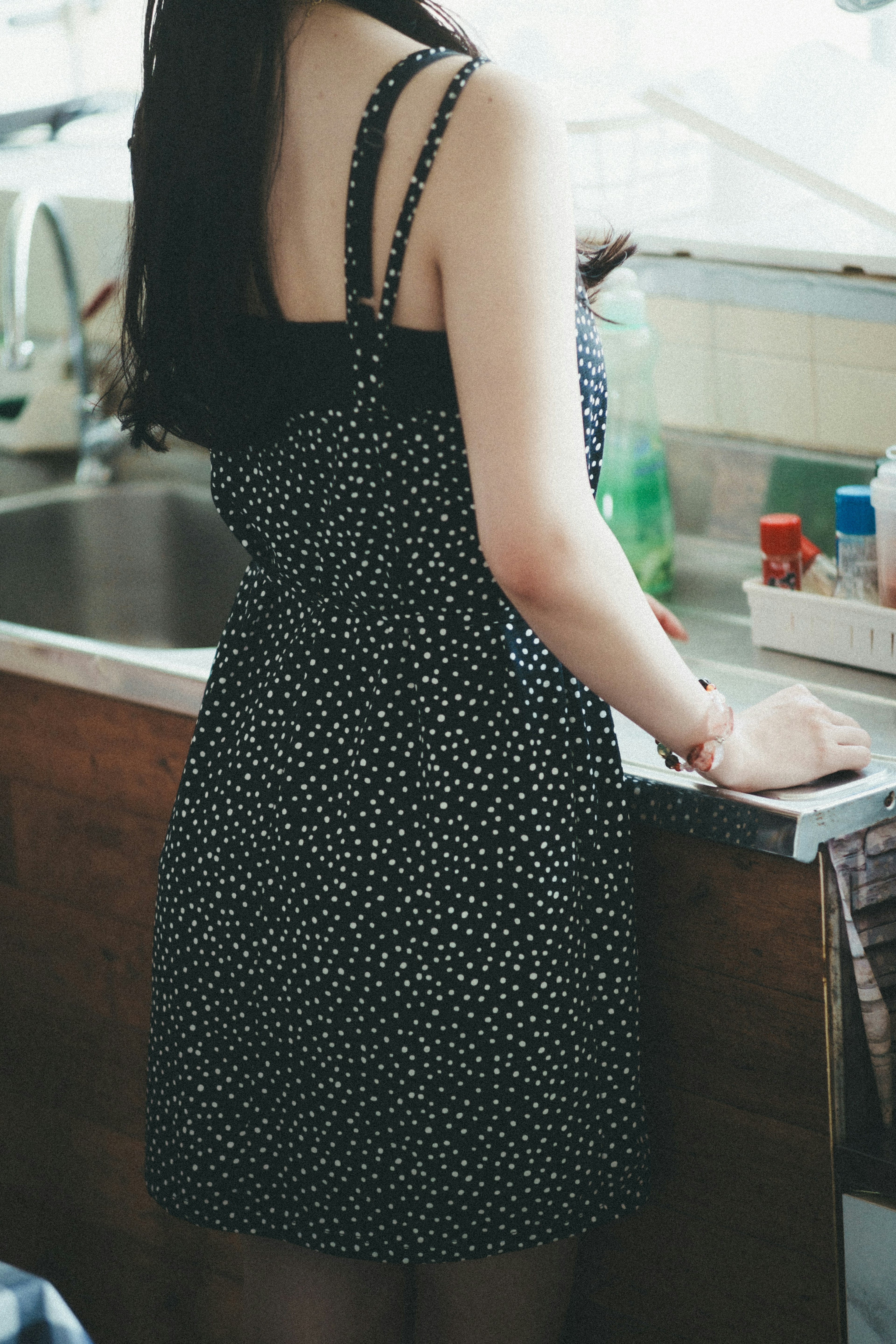 Femme en robe à pois noirs se tenant près de l'évier