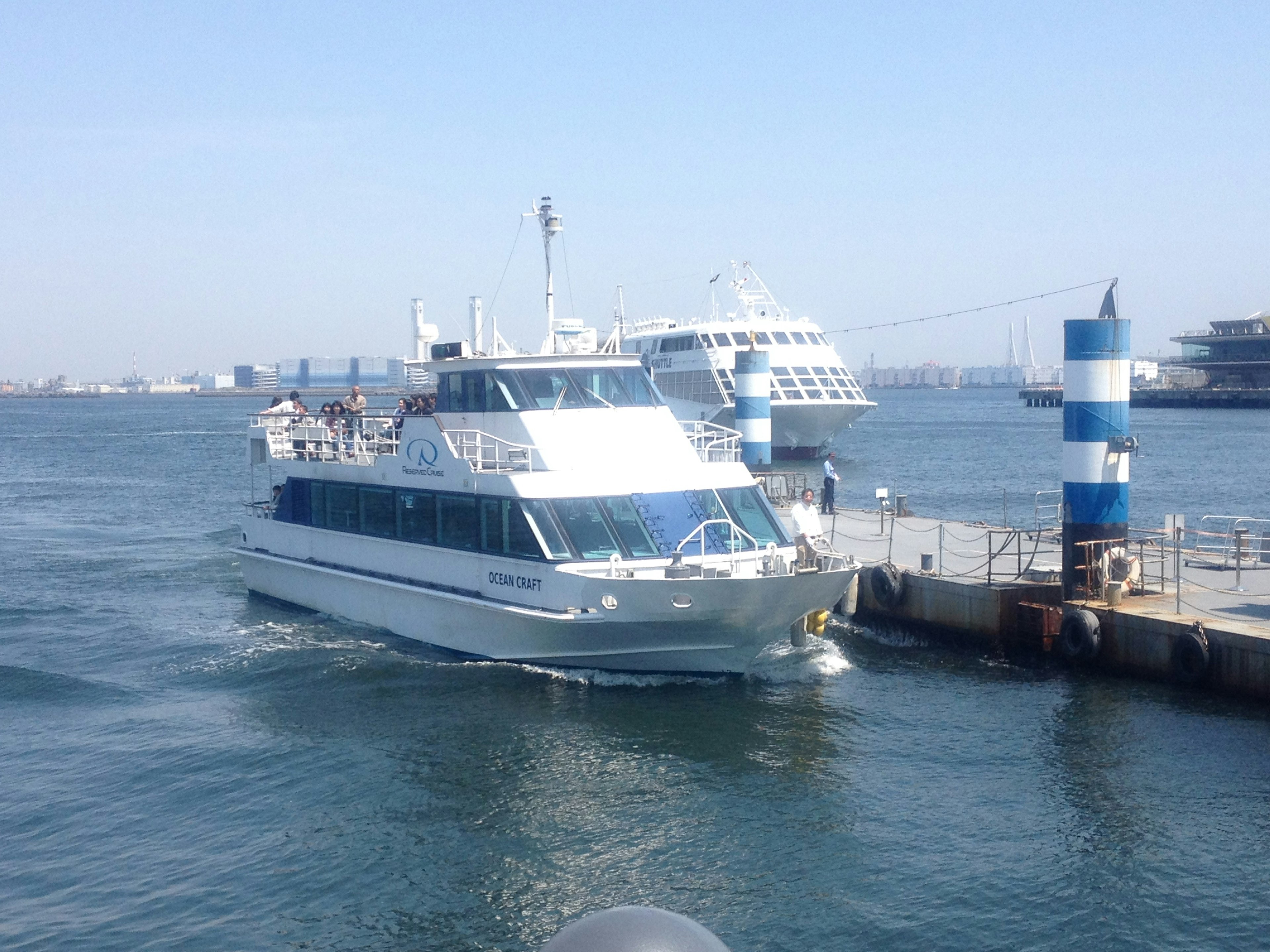 Barco de turismo blanco atracado en el puerto con faro a rayas azules