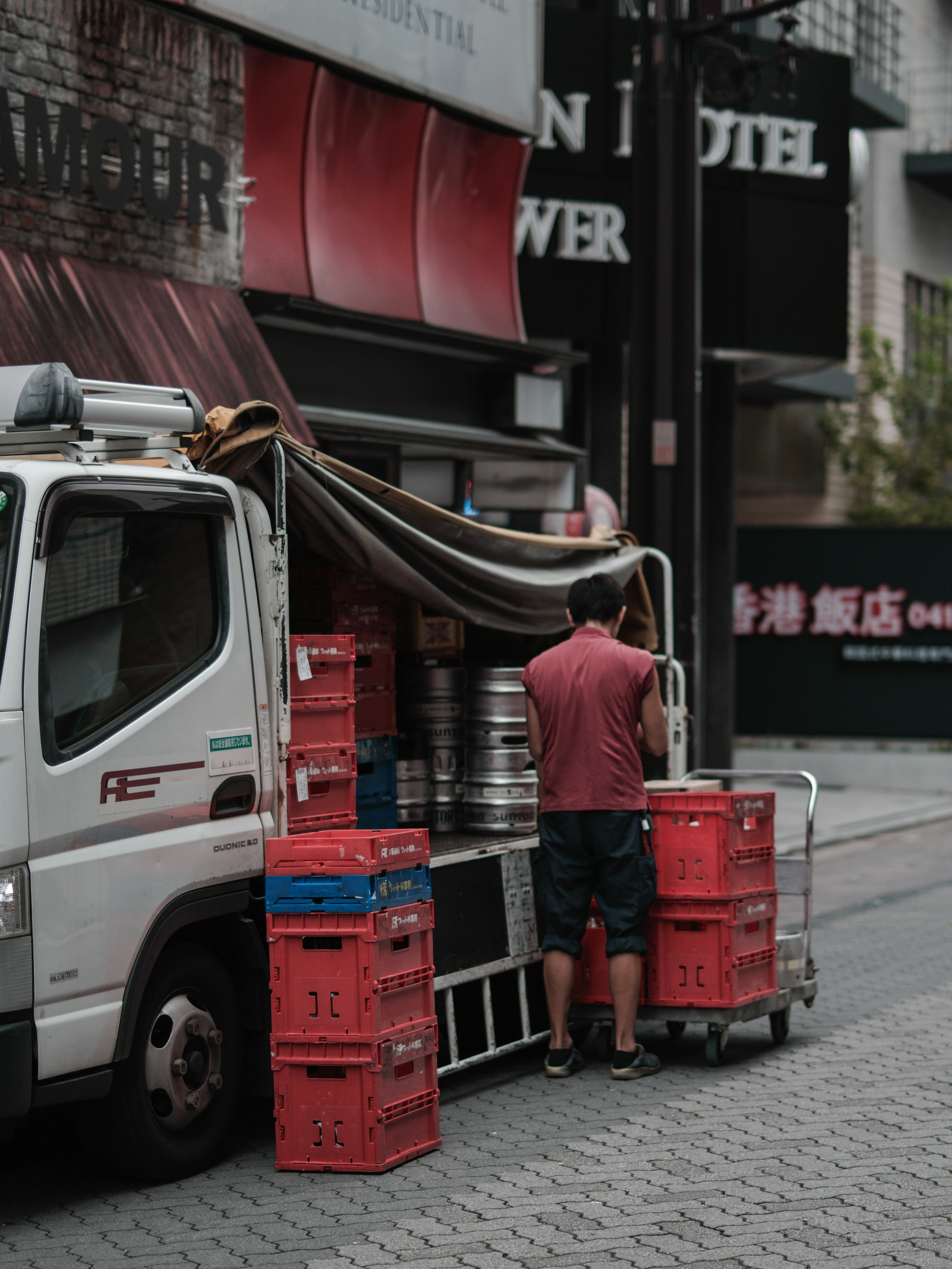 Man working at the back of a truck Red beer crates and silver kegs are visible