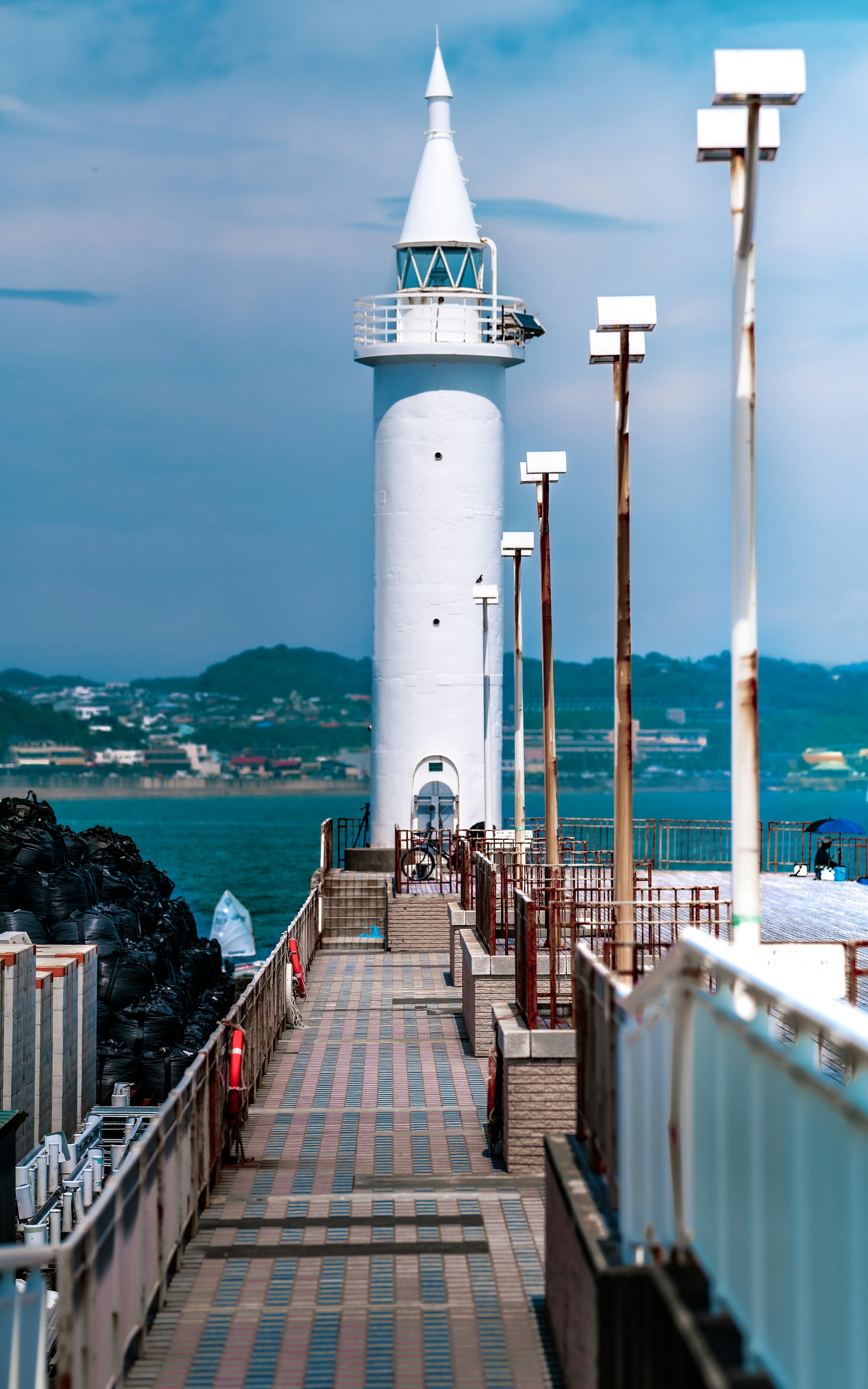 Un phare blanc sur un quai avec un océan bleu en arrière-plan