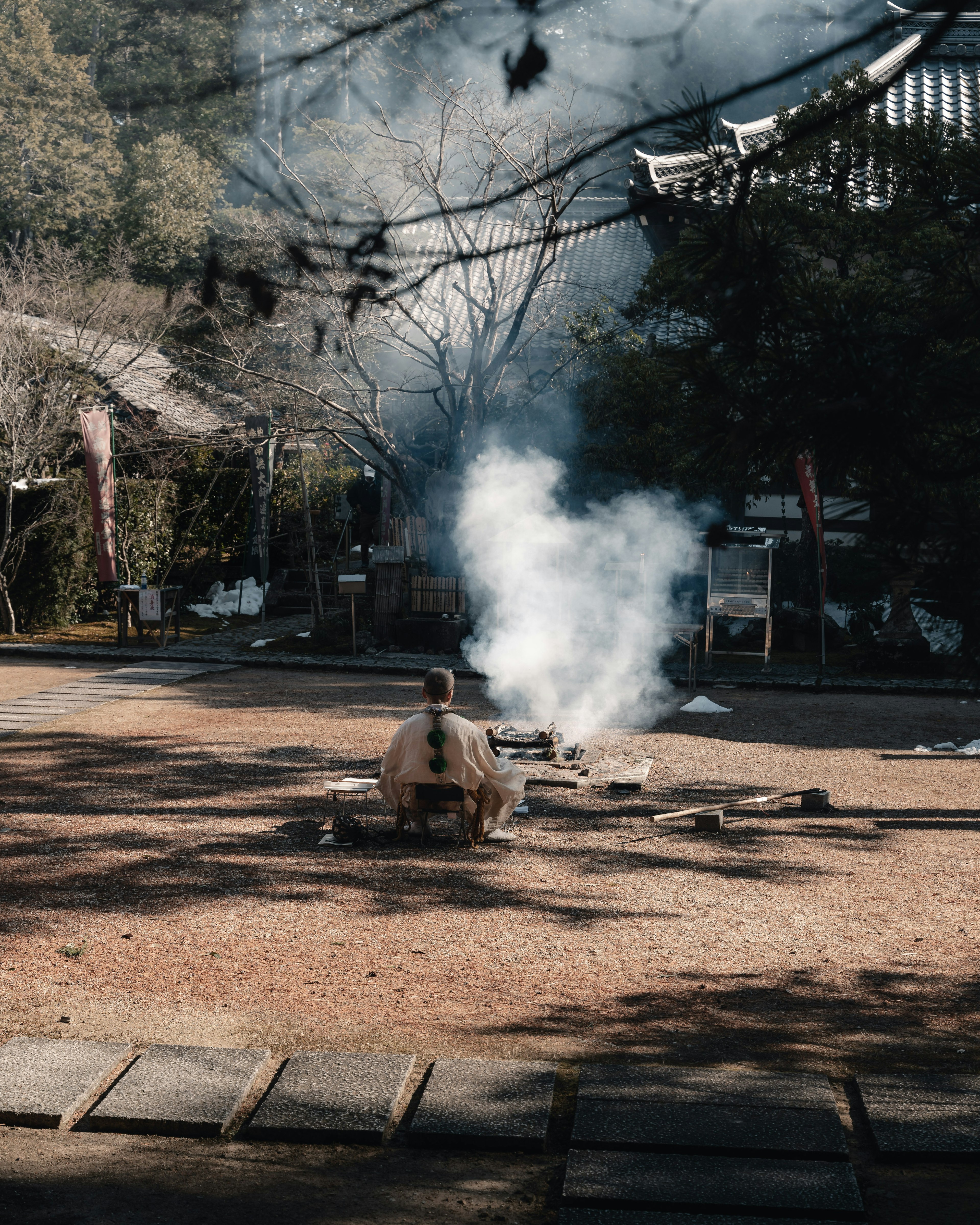 Un hombre sentado en un jardín sereno mirando el humo