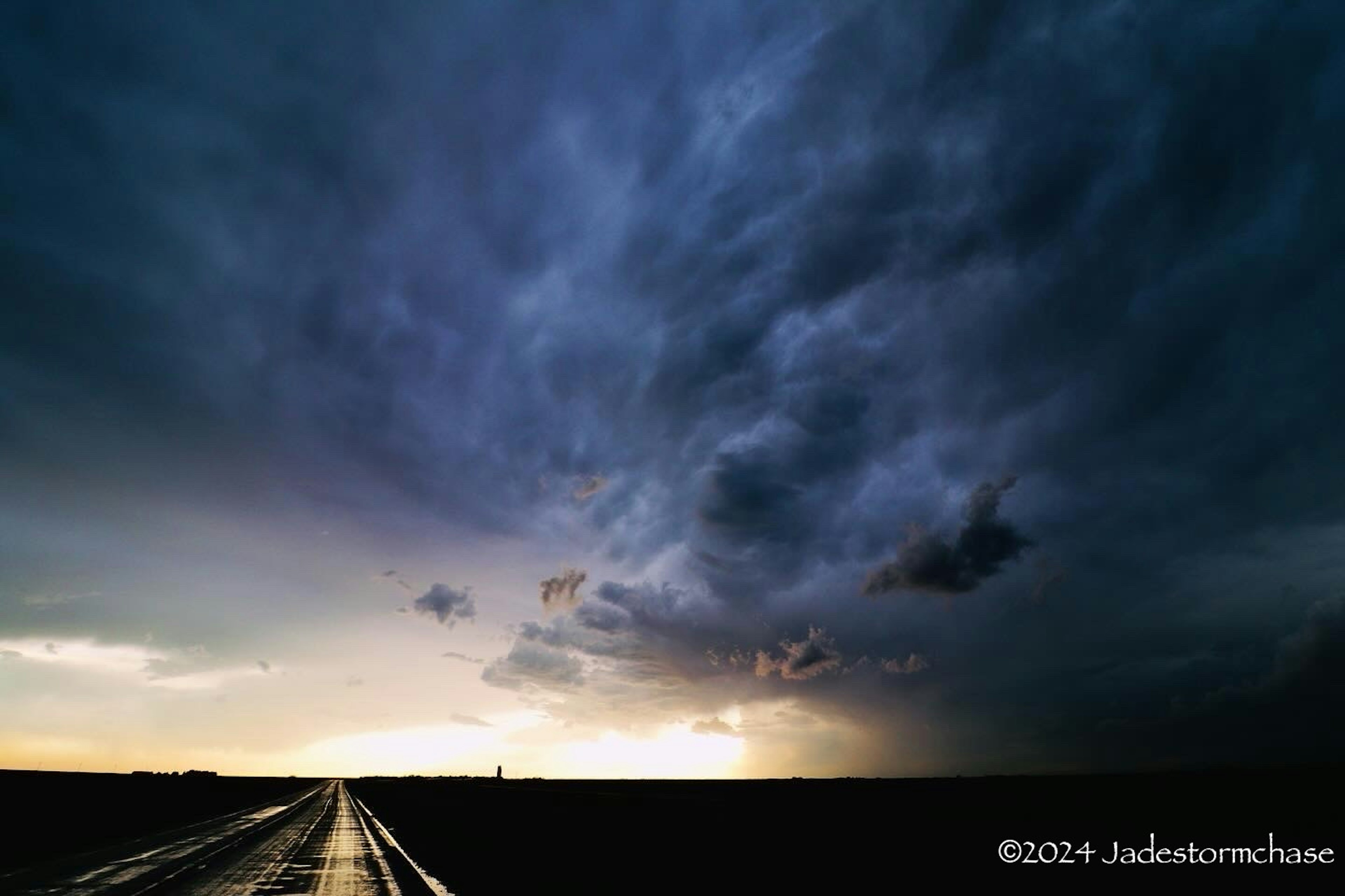 暗い雲が広がる空と雨に濡れた道路の風景