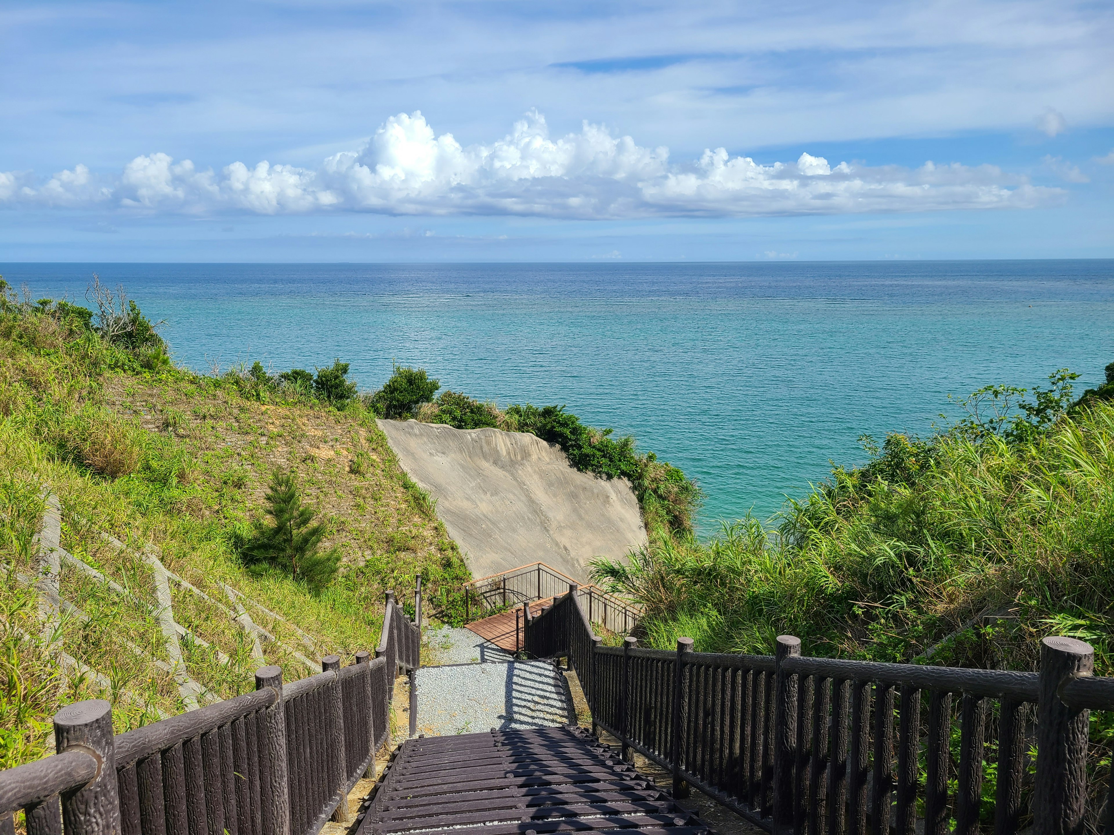 Escalier menant à un océan bleu et des nuages blancs