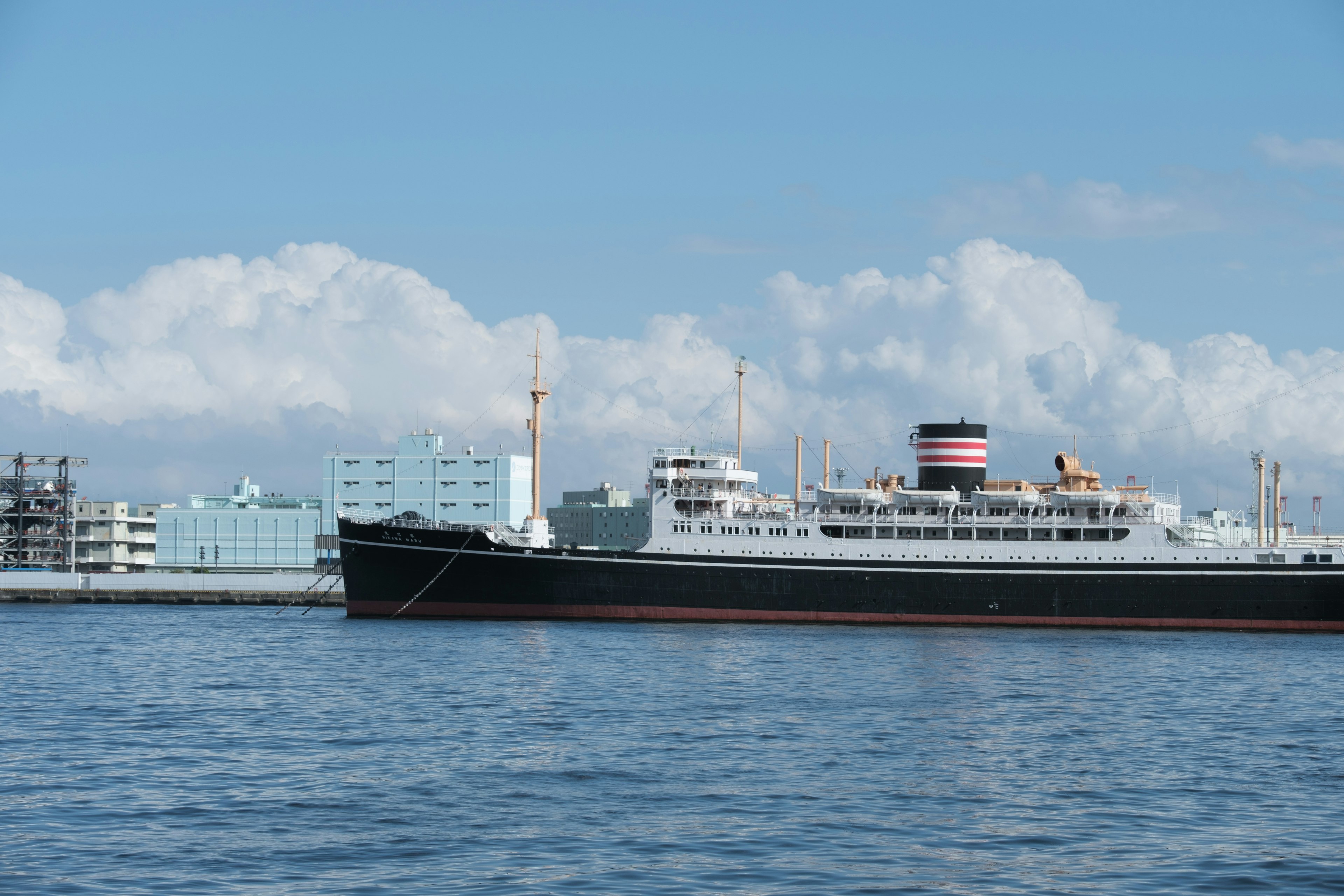 Grand navire de passagers sur l'eau avec des bâtiments en arrière-plan