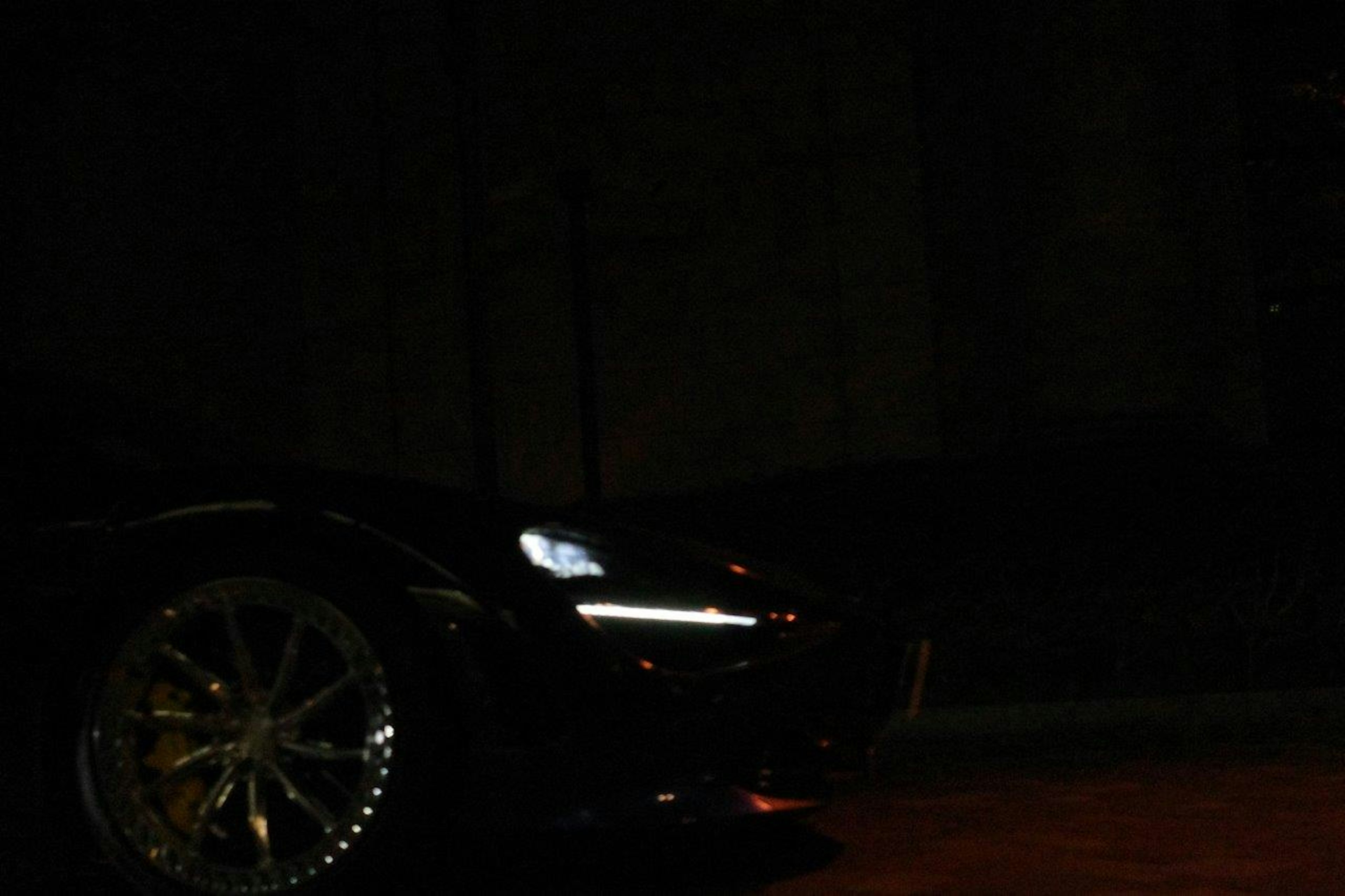 Front view of a sports car illuminated against a dark background