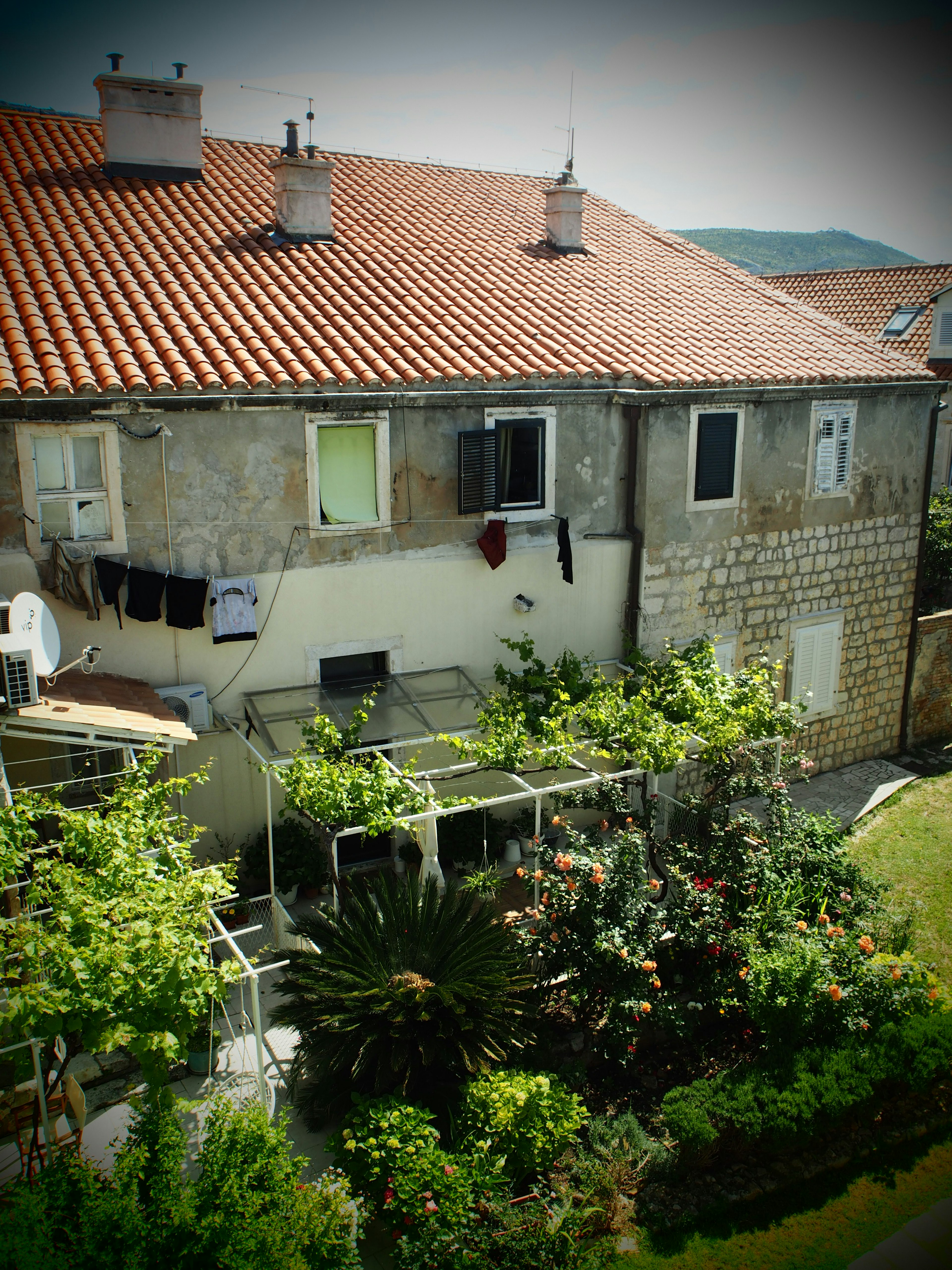 Maison en pierre avec un toit rouge entourée de verdure luxuriante