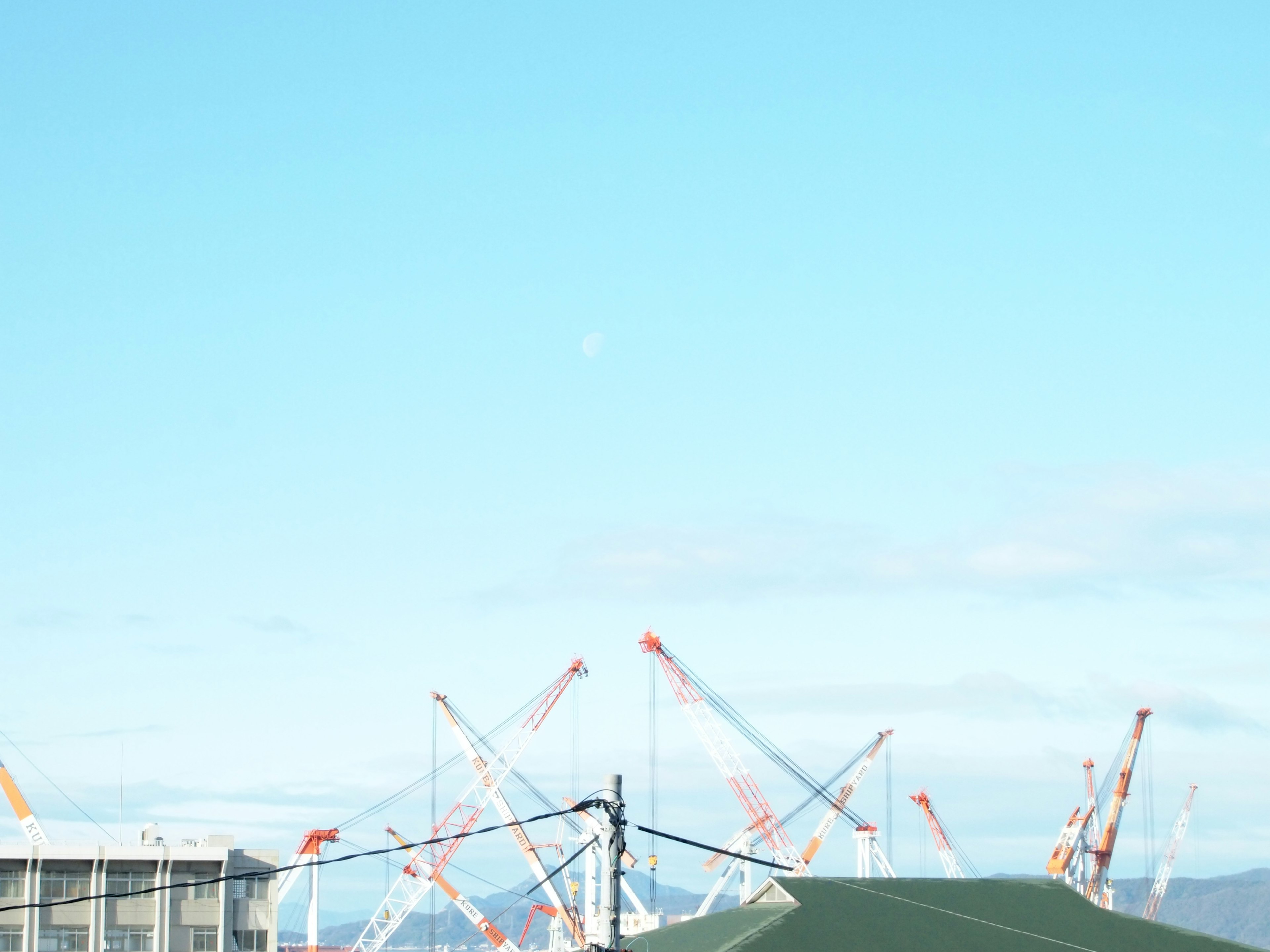 Paesaggio industriale con gru sotto un cielo blu chiaro