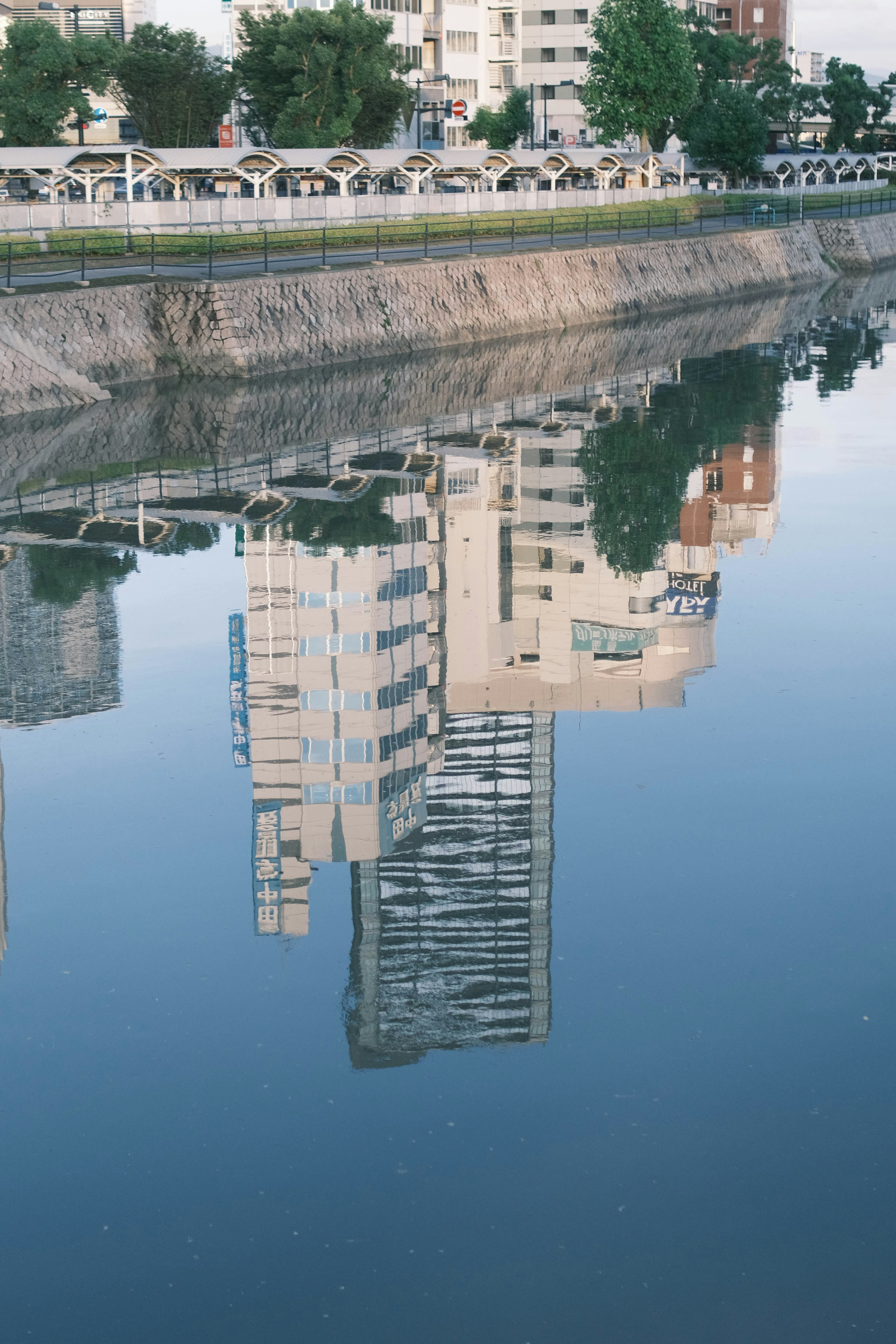 Reflexion von Gebäuden im Fluss mit umgebender Grünfläche