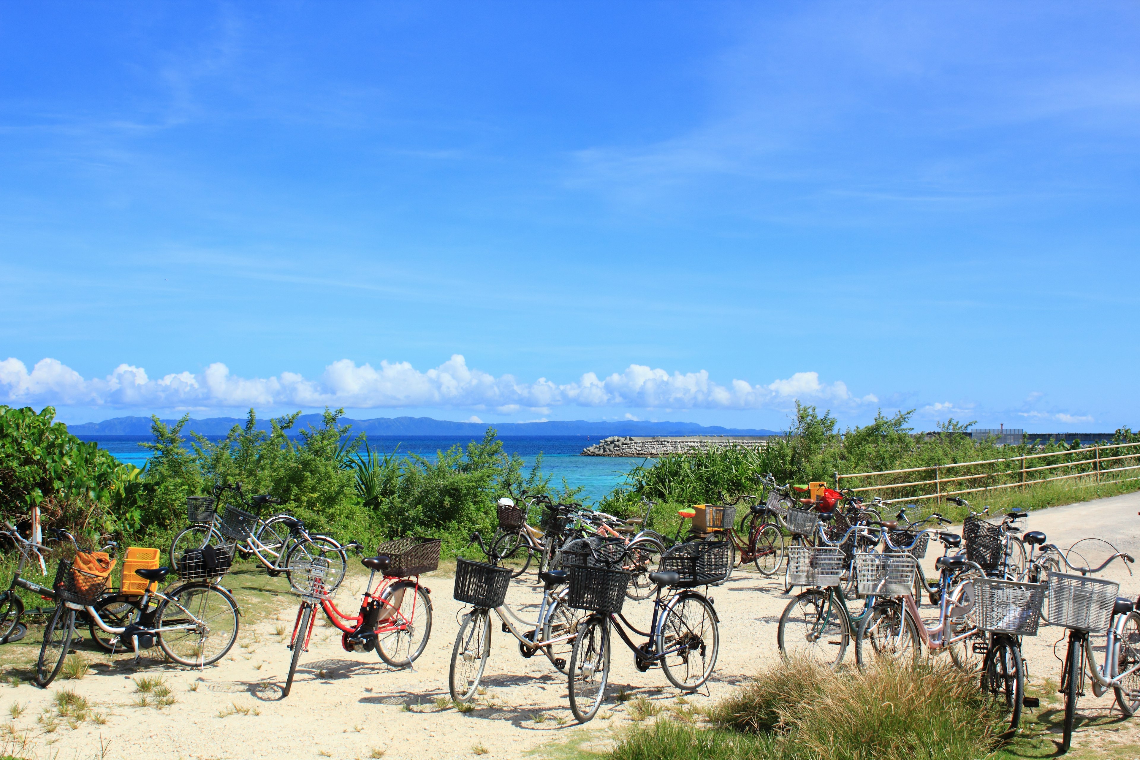 Vélos garés sur un chemin de sable avec un ciel bleu et l'océan en arrière-plan