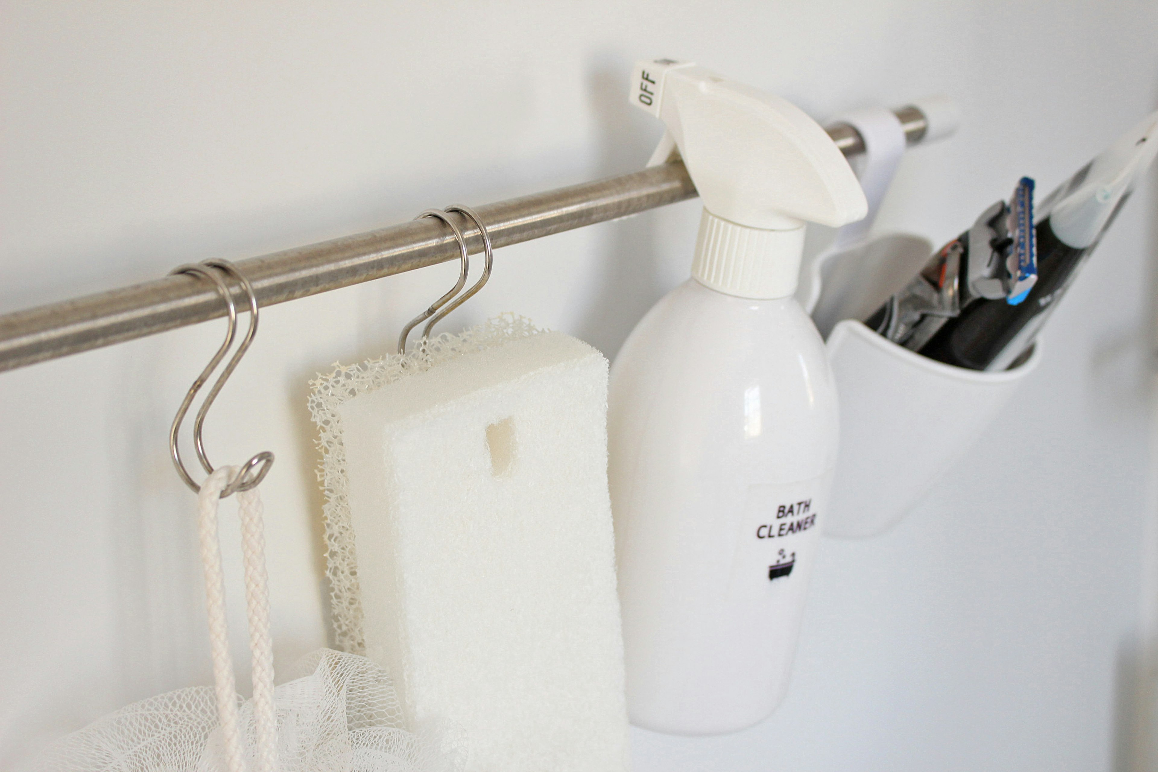 Almacenamiento de pared simple con un bote de spray blanco y una esponja colgante