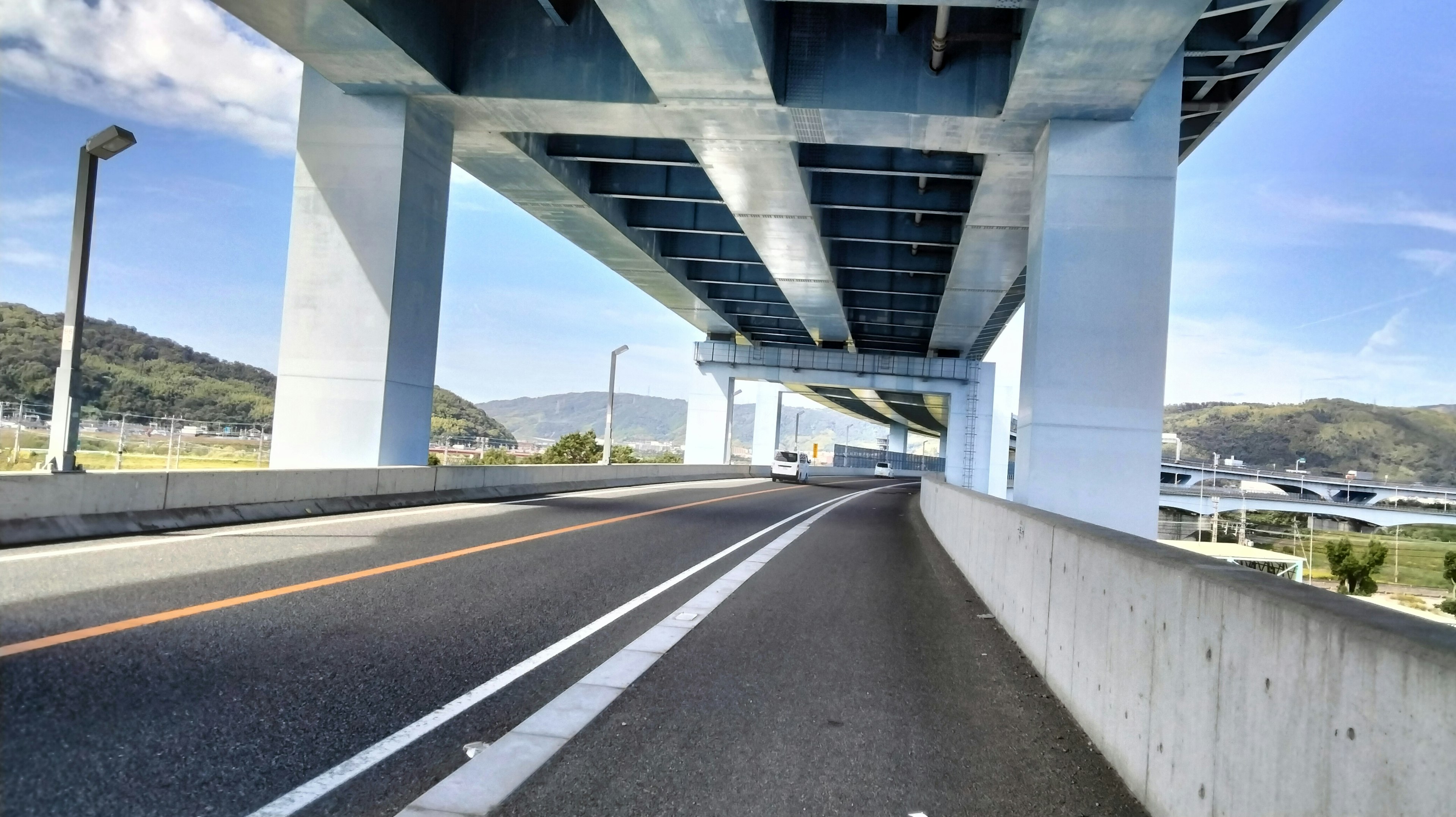 Vue sous une autoroute élevée avec des piliers en béton et une route courbée