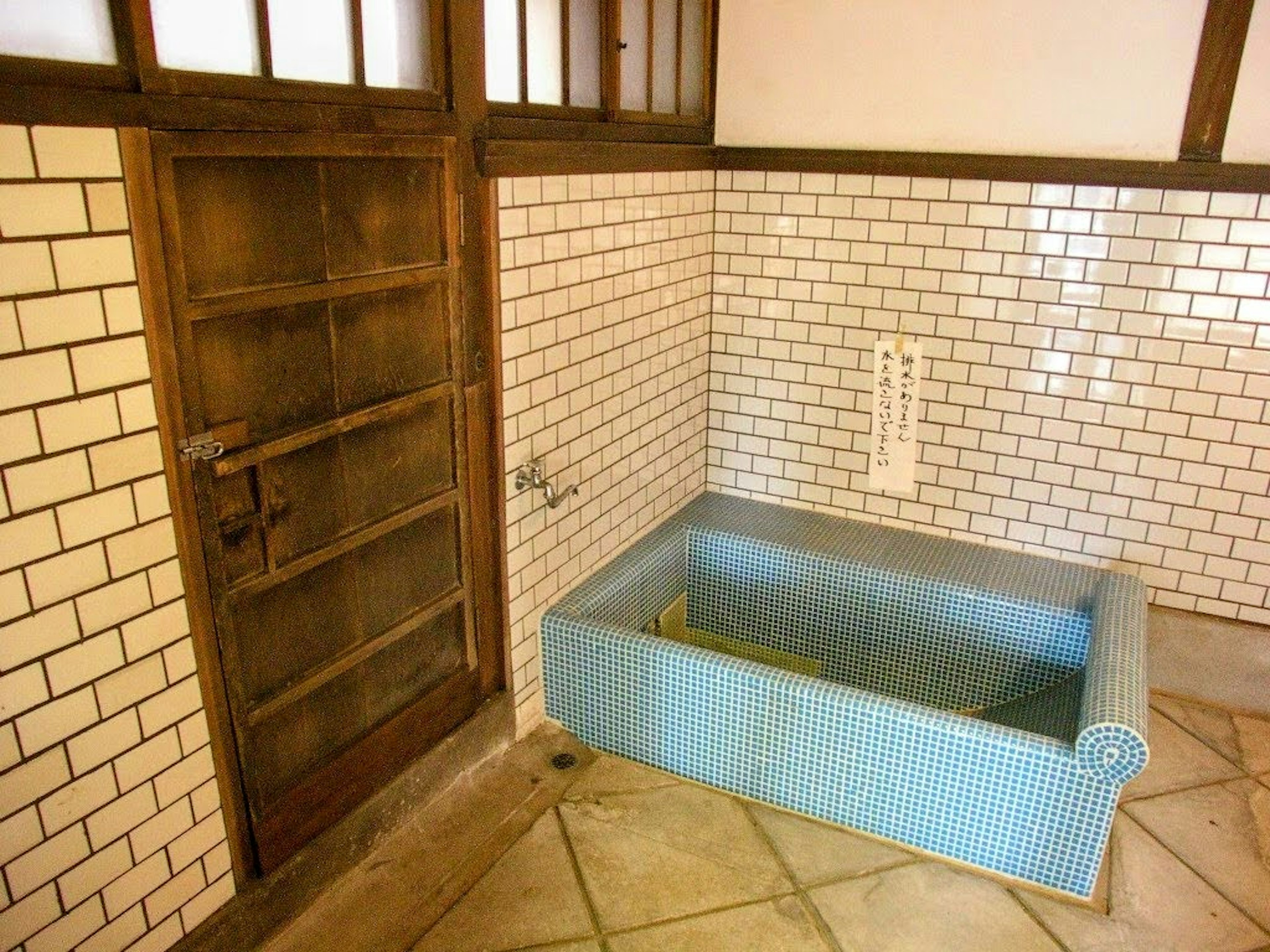 Innenraum eines traditionellen Zimmers mit einer blauen Badewanne gefliester Boden und Ziegelwände