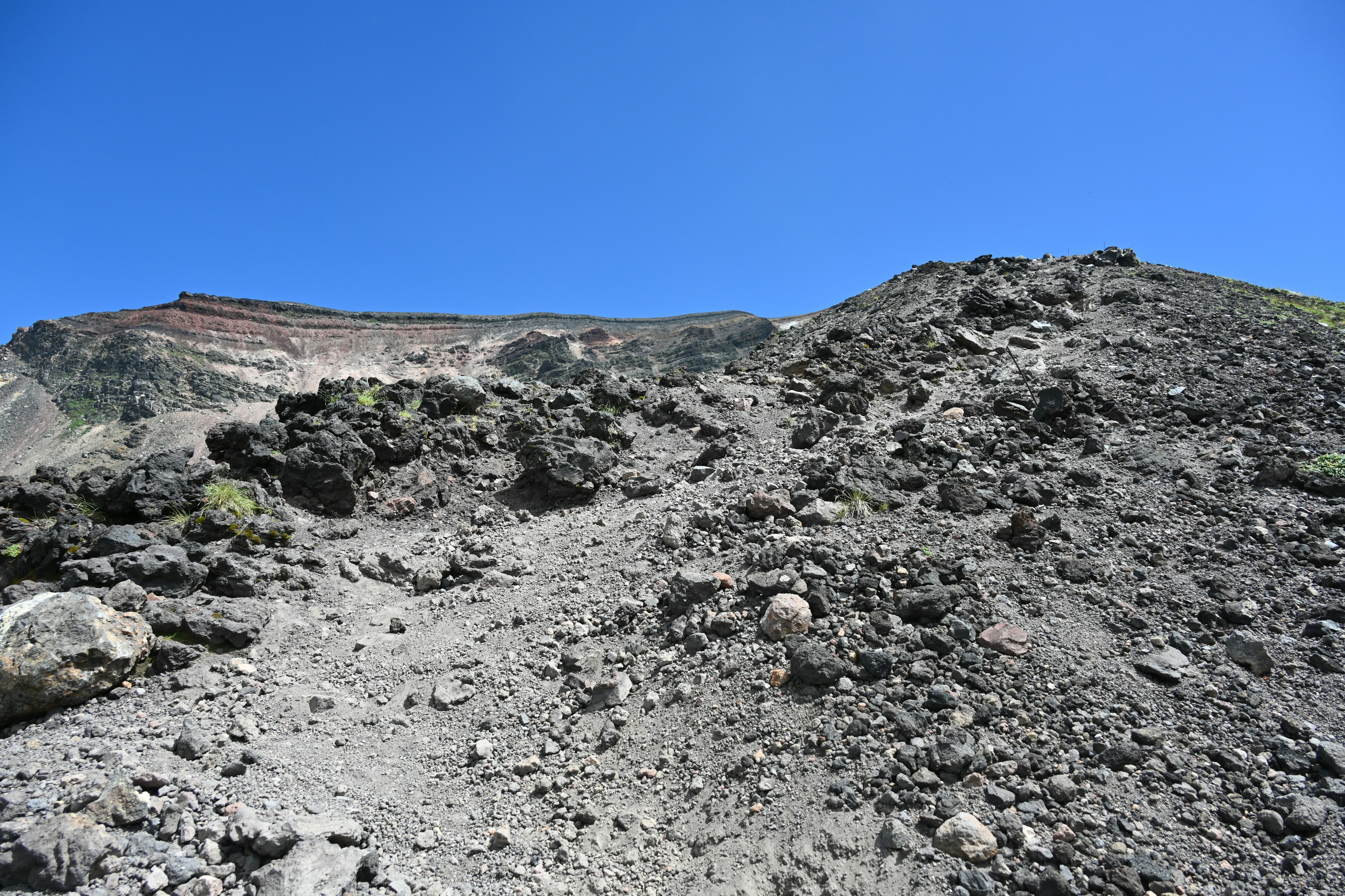 Pente volcanique avec chemin rocheux sous un ciel bleu