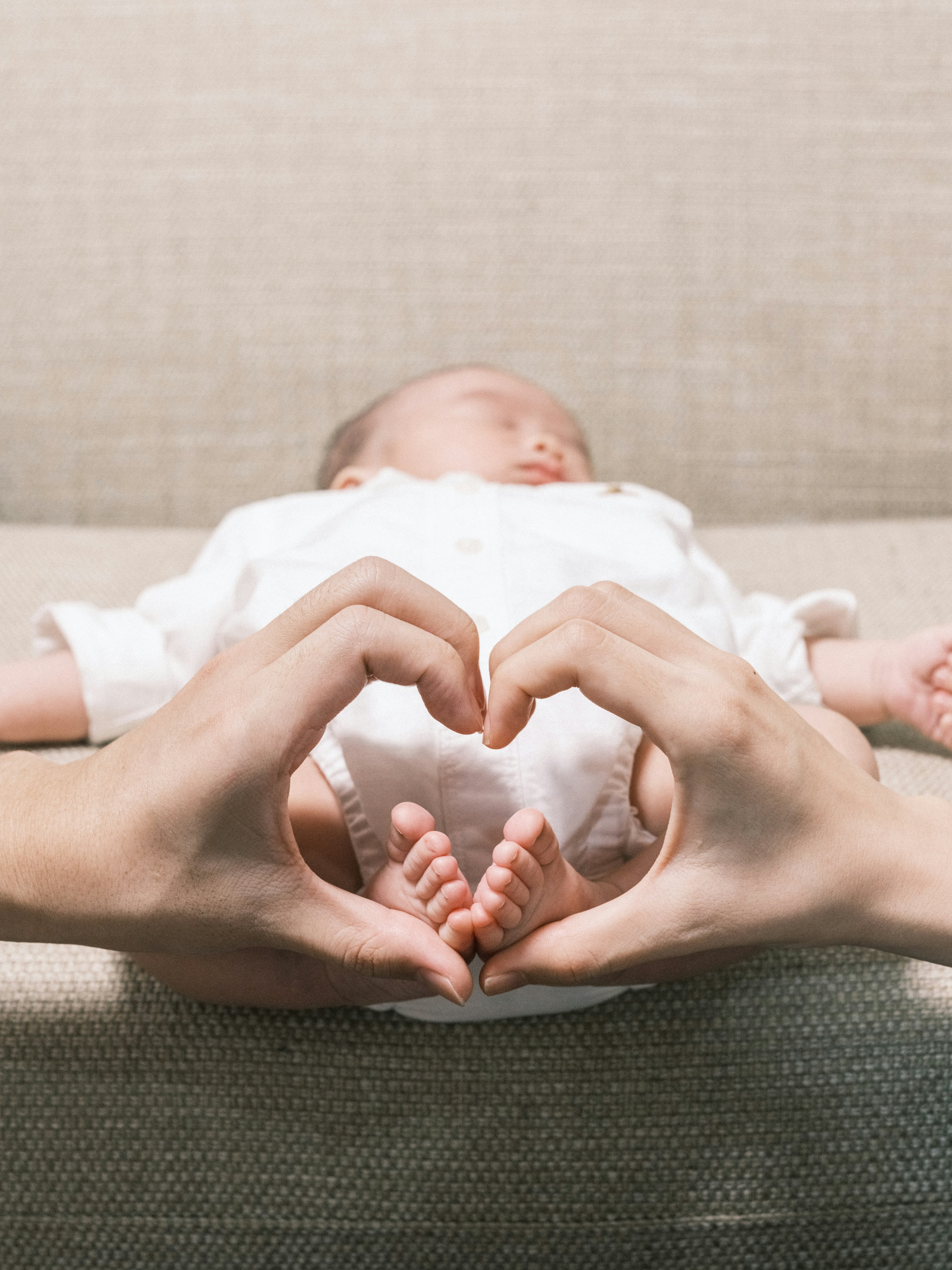 Tangan membentuk bentuk hati di sekitar bayi yang sedang tidur