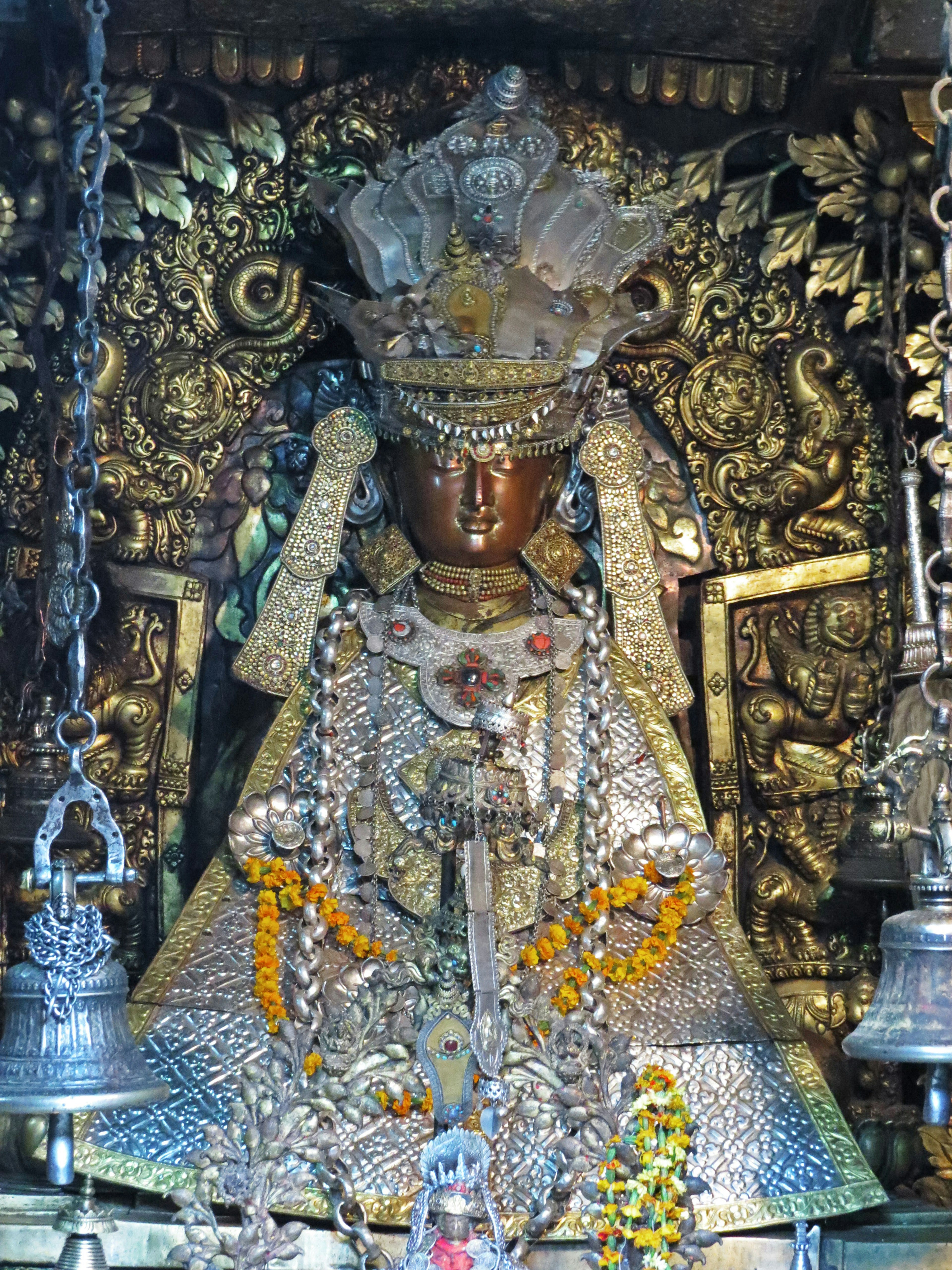 Statue de divinité ornée de manière élaborée avec des sculptures métalliques complexes