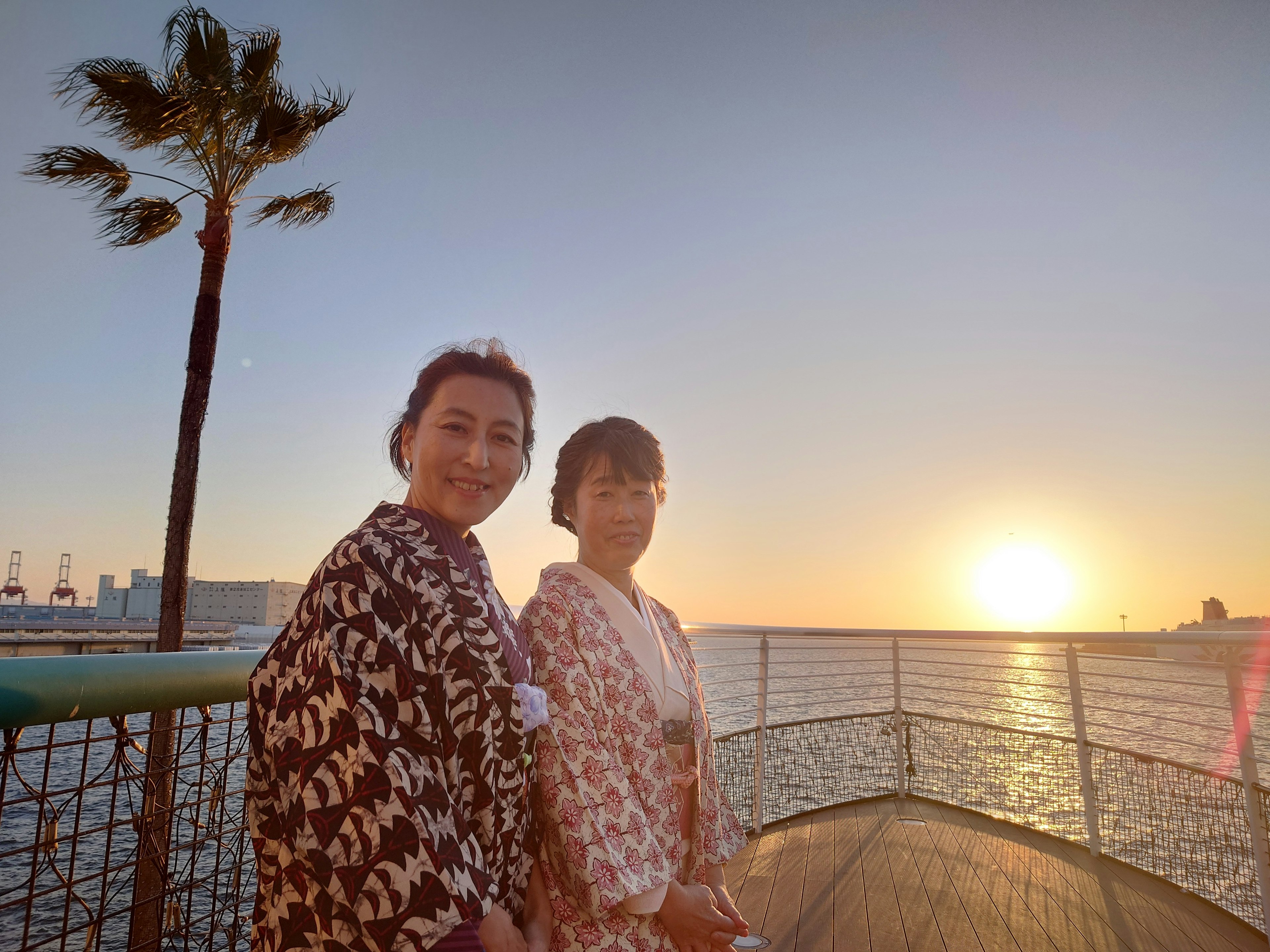 Zwei Frauen in traditioneller Kleidung posieren mit einem Sonnenuntergang im Hintergrund