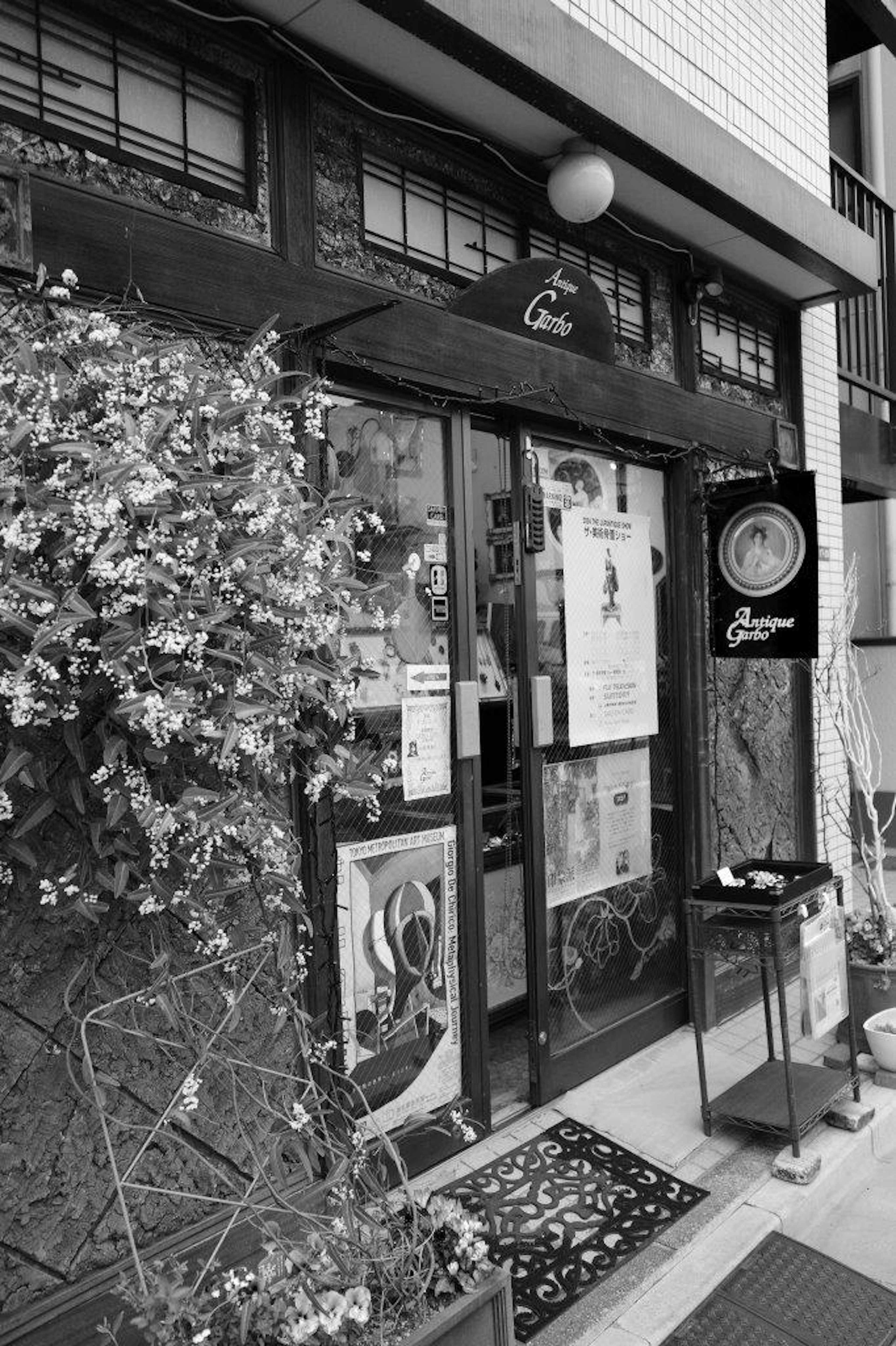 Black and white exterior of a restaurant with floral decorations at the entrance