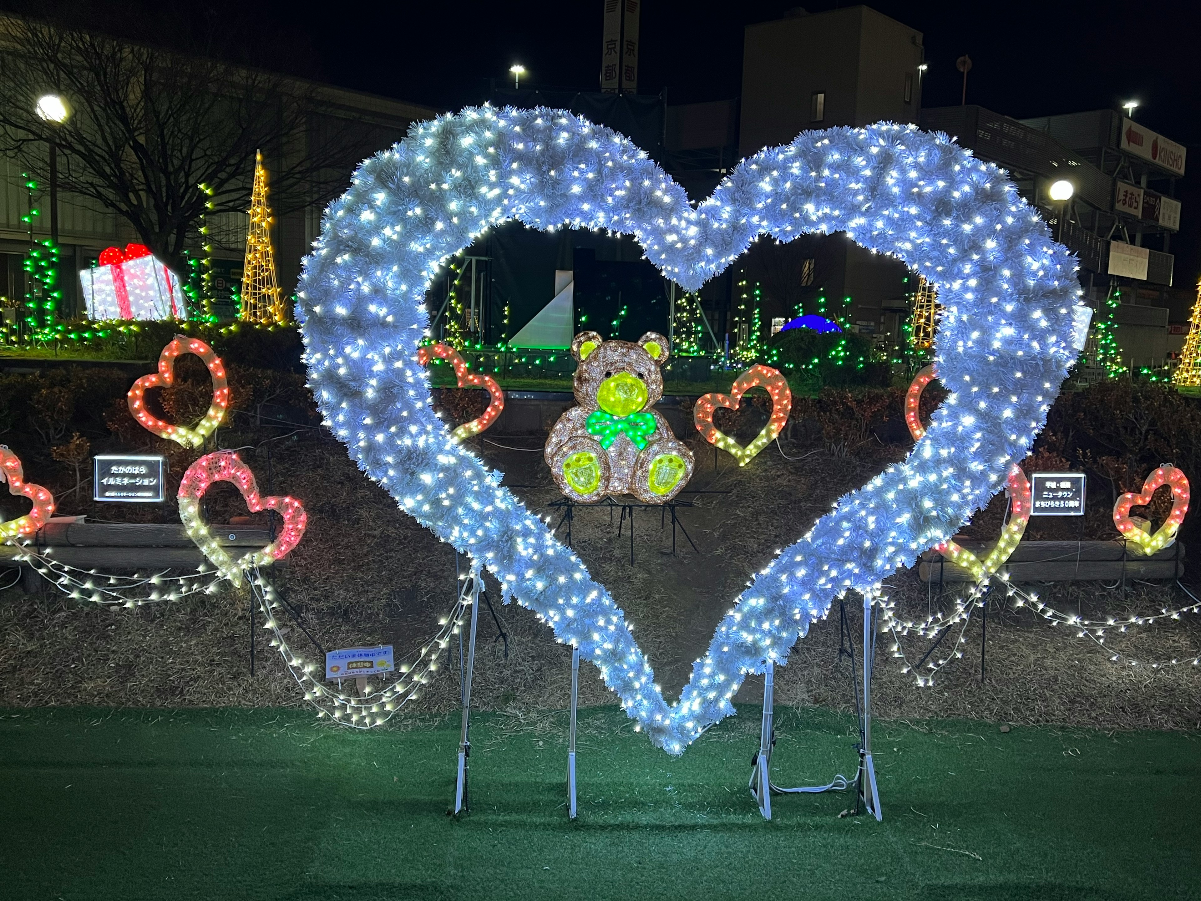 Décoration lumineuse en forme de cœur avec un ours en peluche au centre entouré de cœurs lumineux