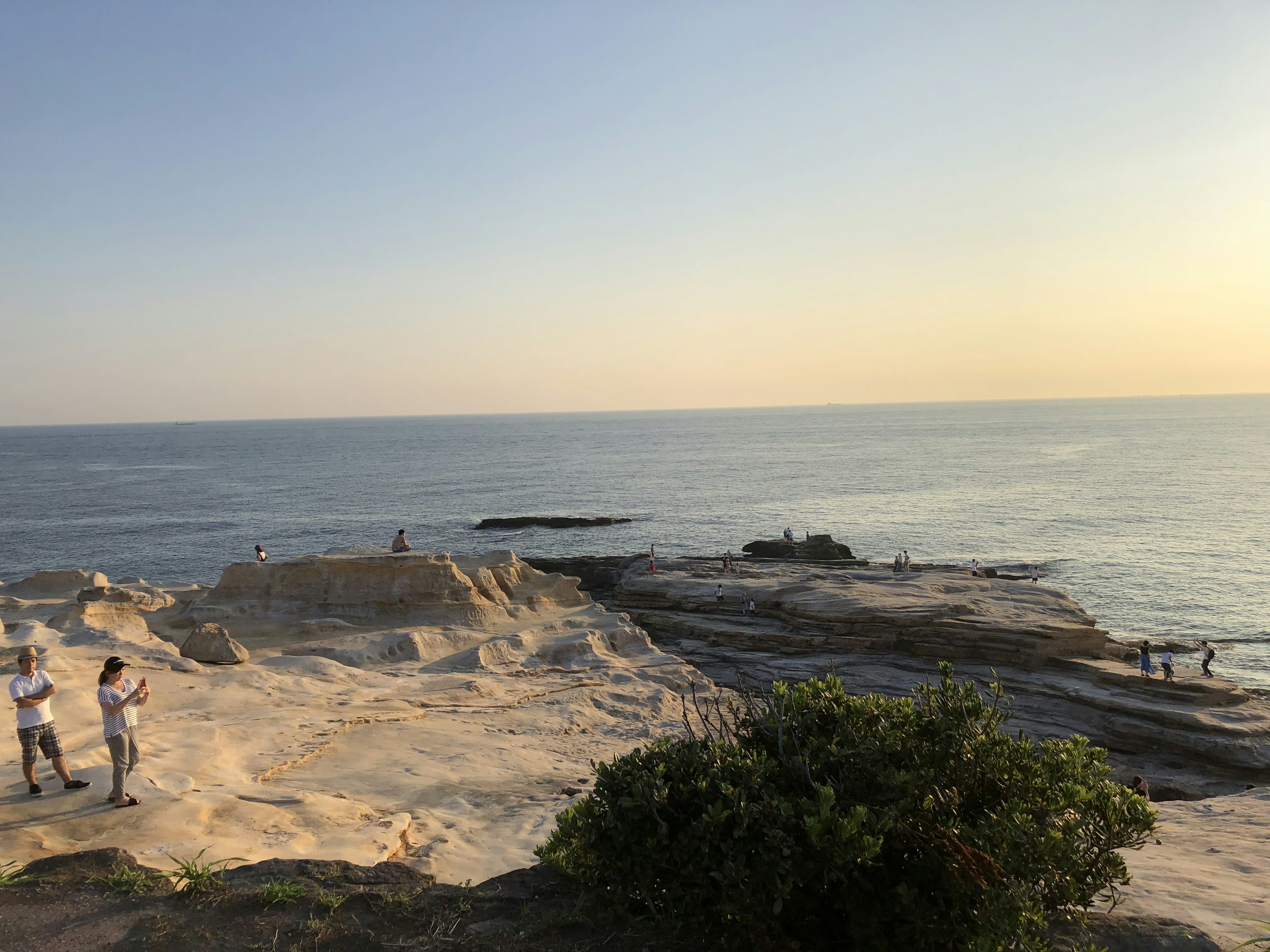 夕日の海岸に立つ人々と静かな海