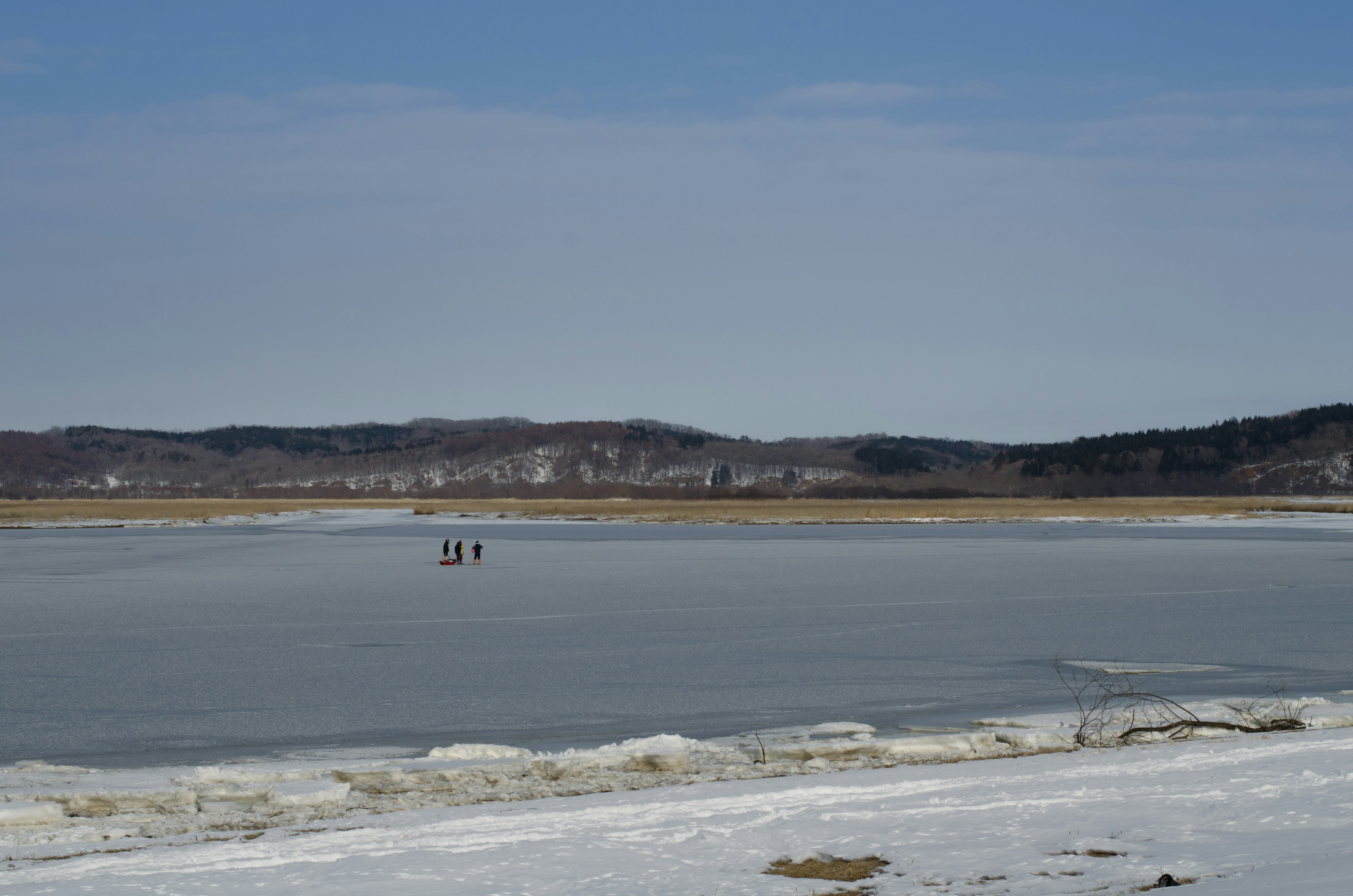 Des personnes debout sur un lac gelé avec des montagnes au loin