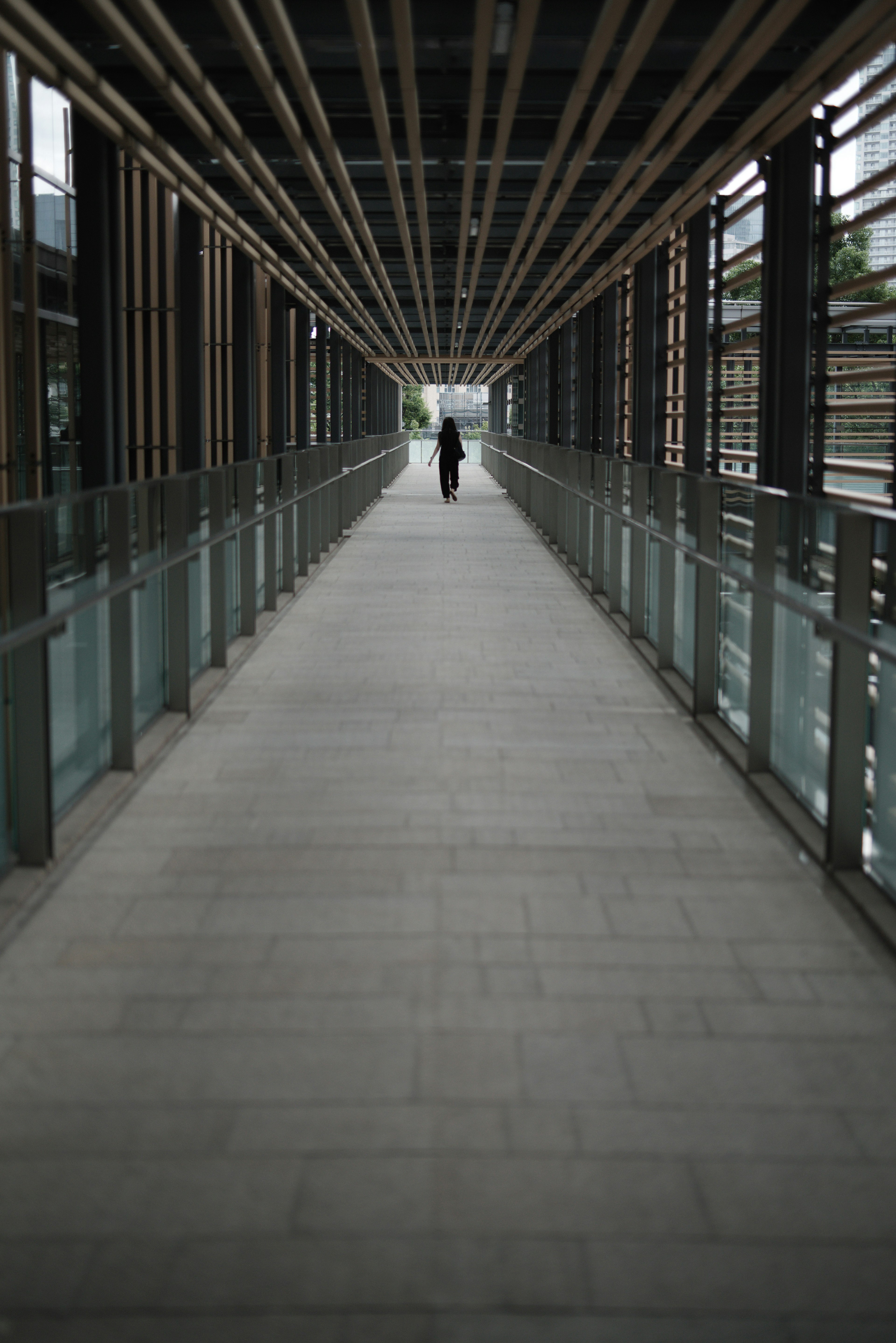 Schatten einer Person in einem langen Korridor mit Glasgeländern in einem modernen Gebäude