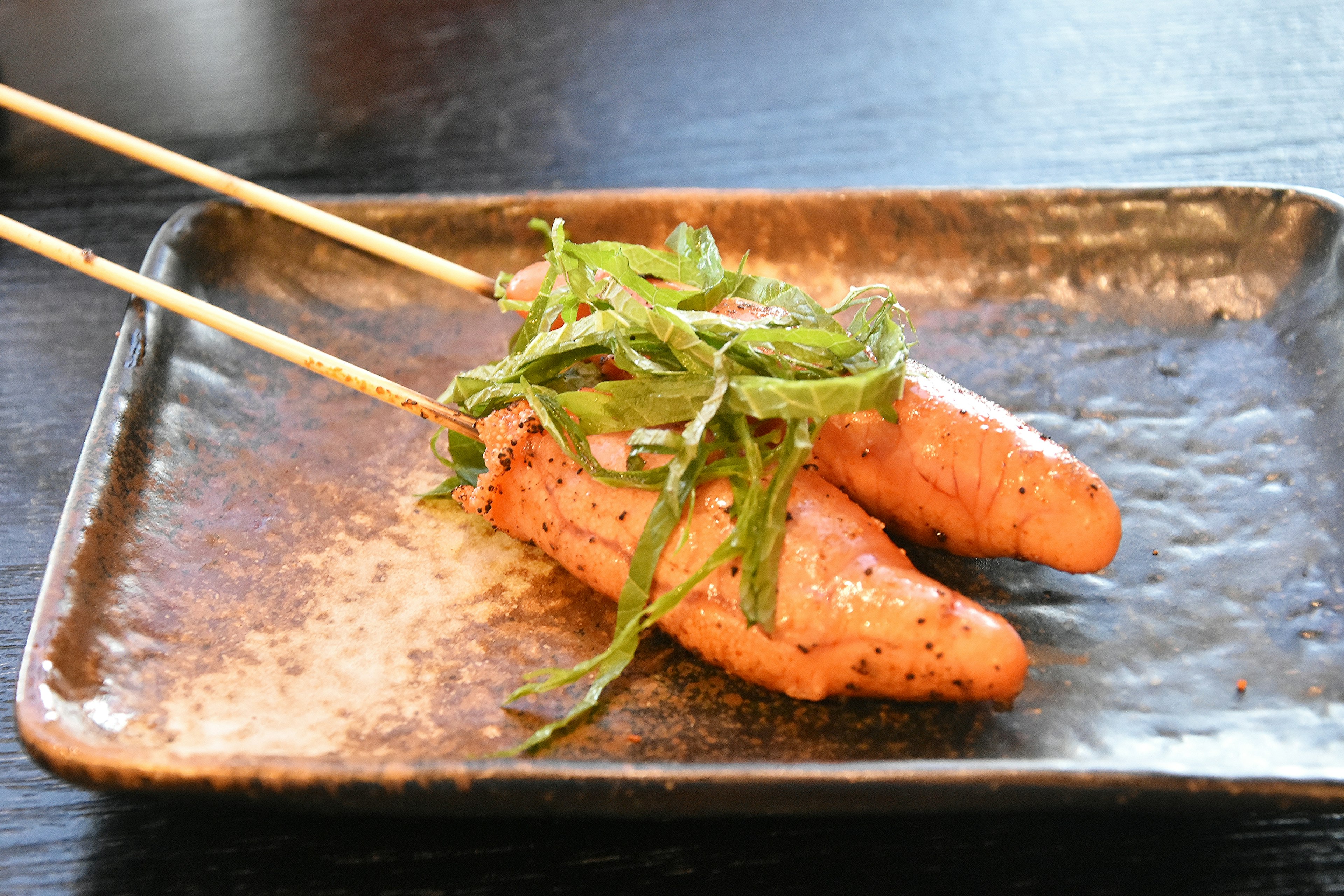 Plat de poisson grillé servi sur une assiette avec des baguettes