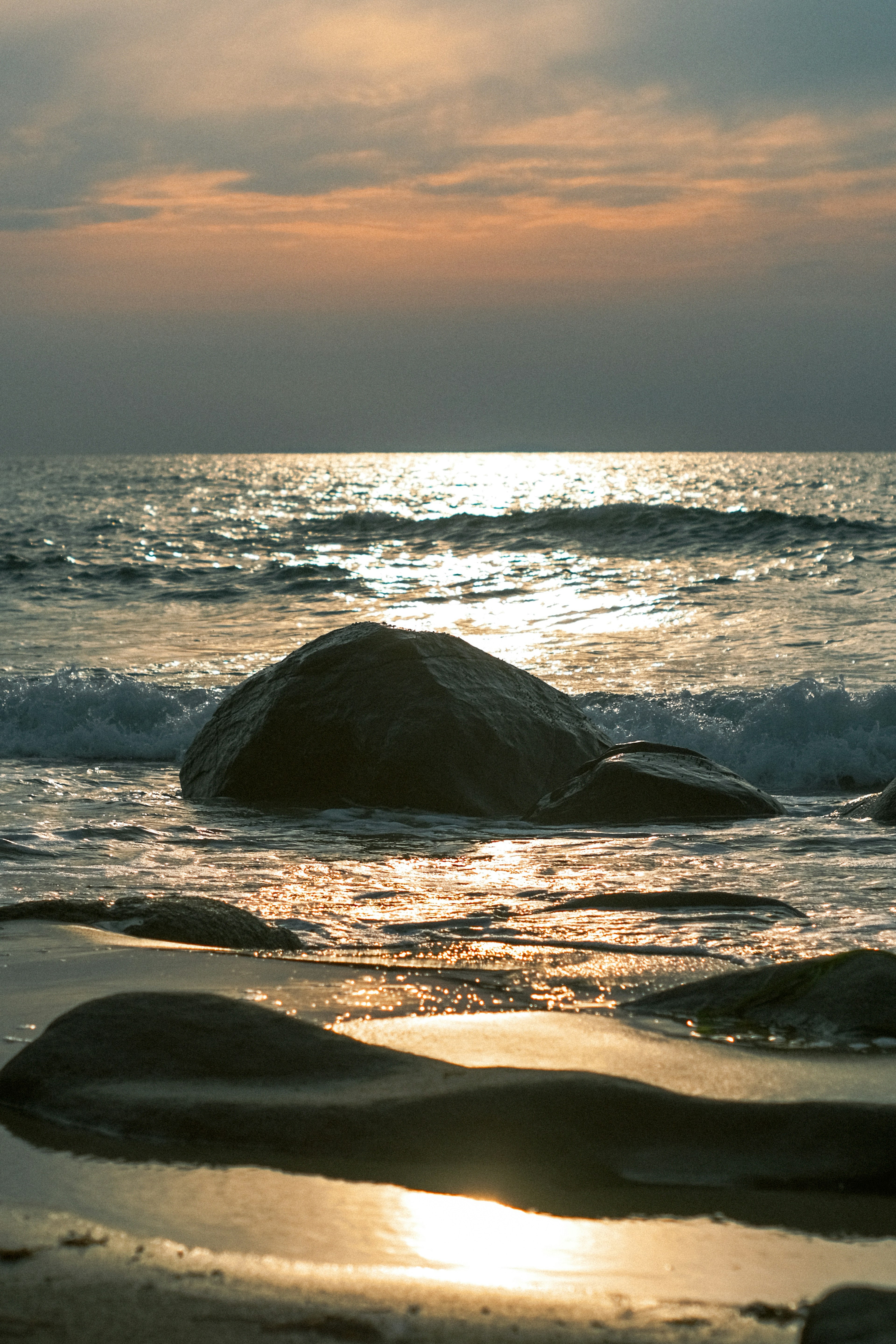 Scena di tramonto costiero con onde che si infrangono contro le rocce