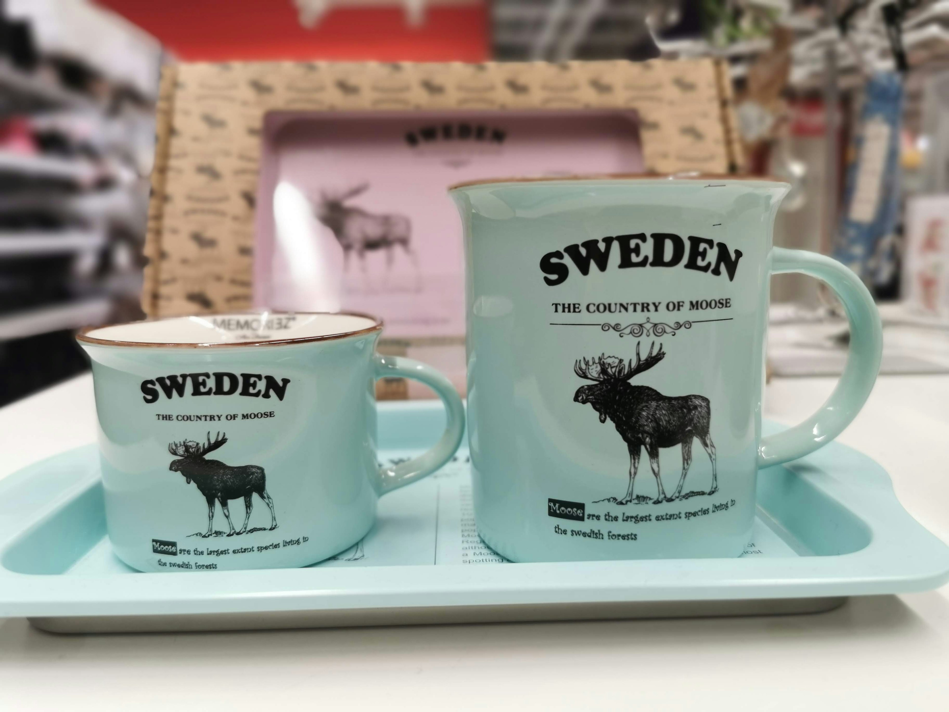 Two blue cups featuring Swedish design with moose illustrations on a tray