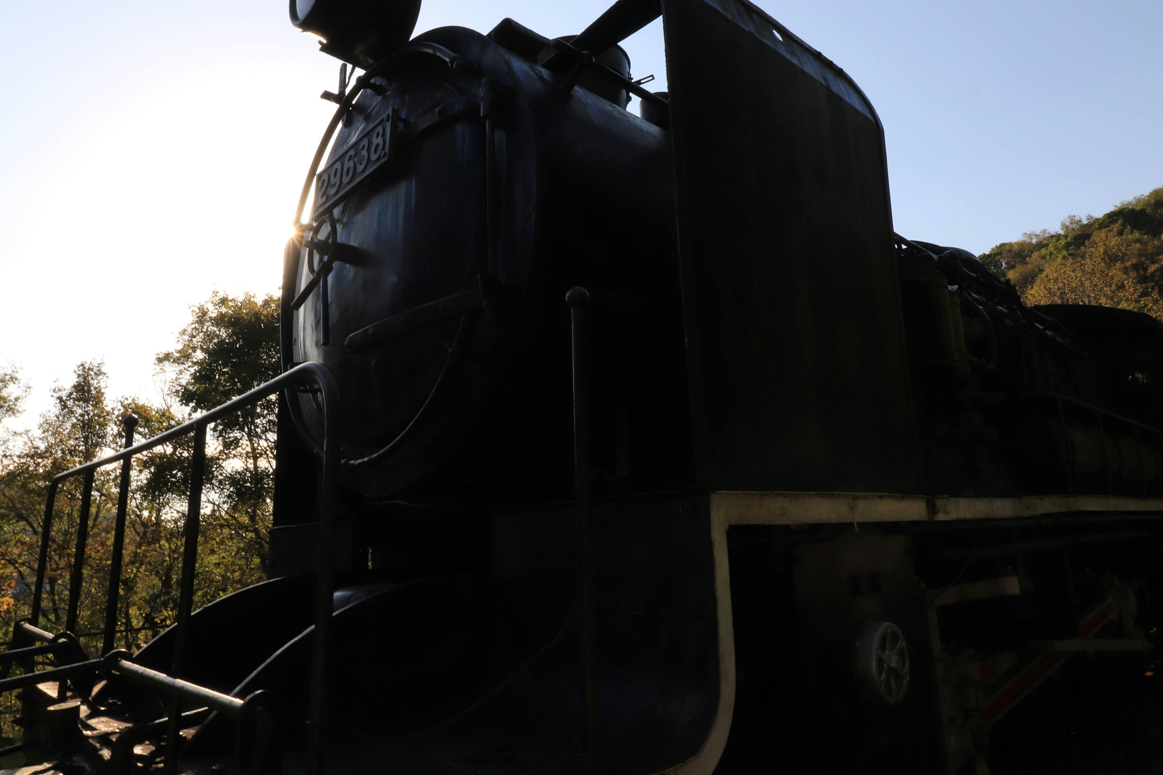 Silhouette of a steam locomotive with sunlight in the background