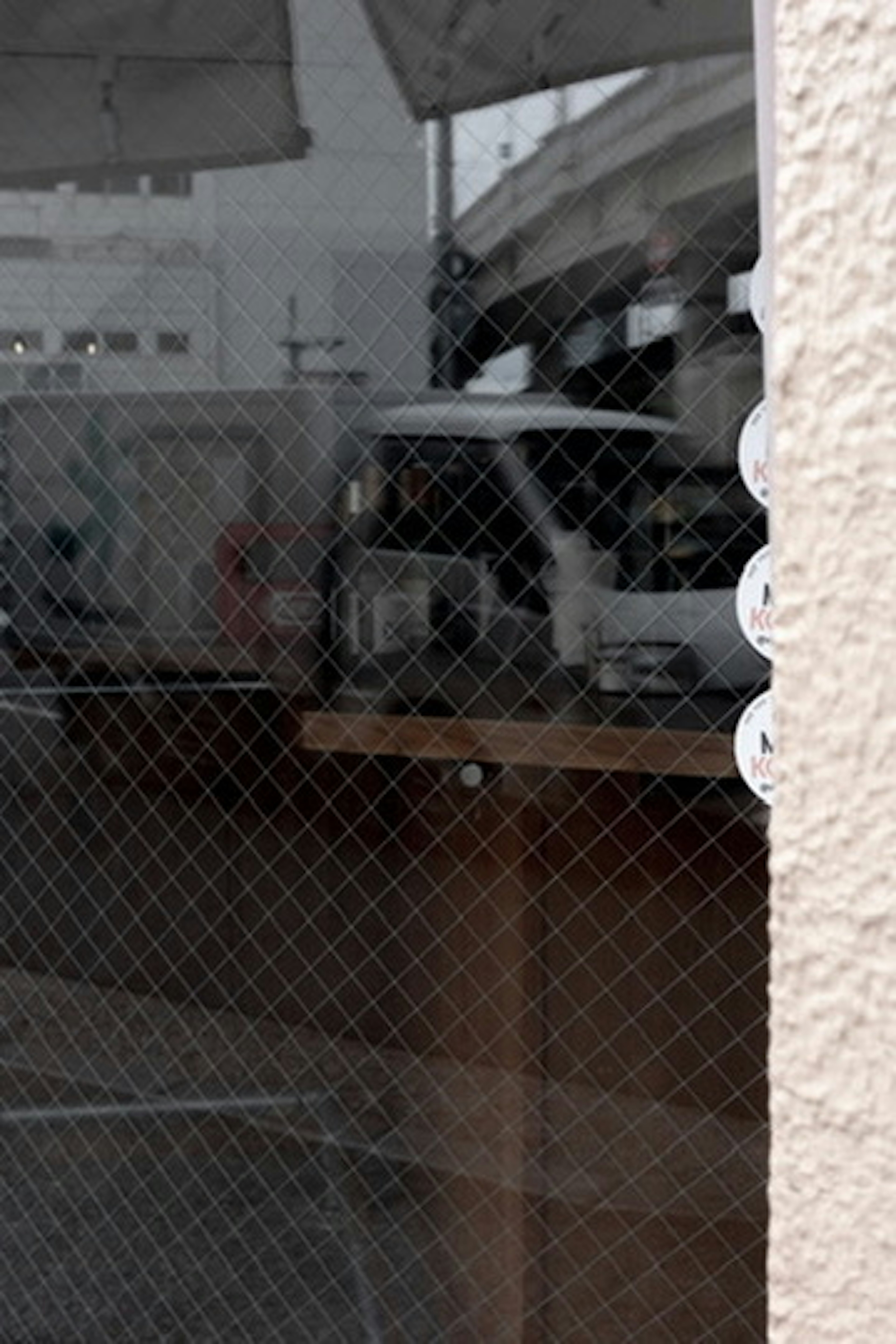 Reflection of a vehicle and fence in a window