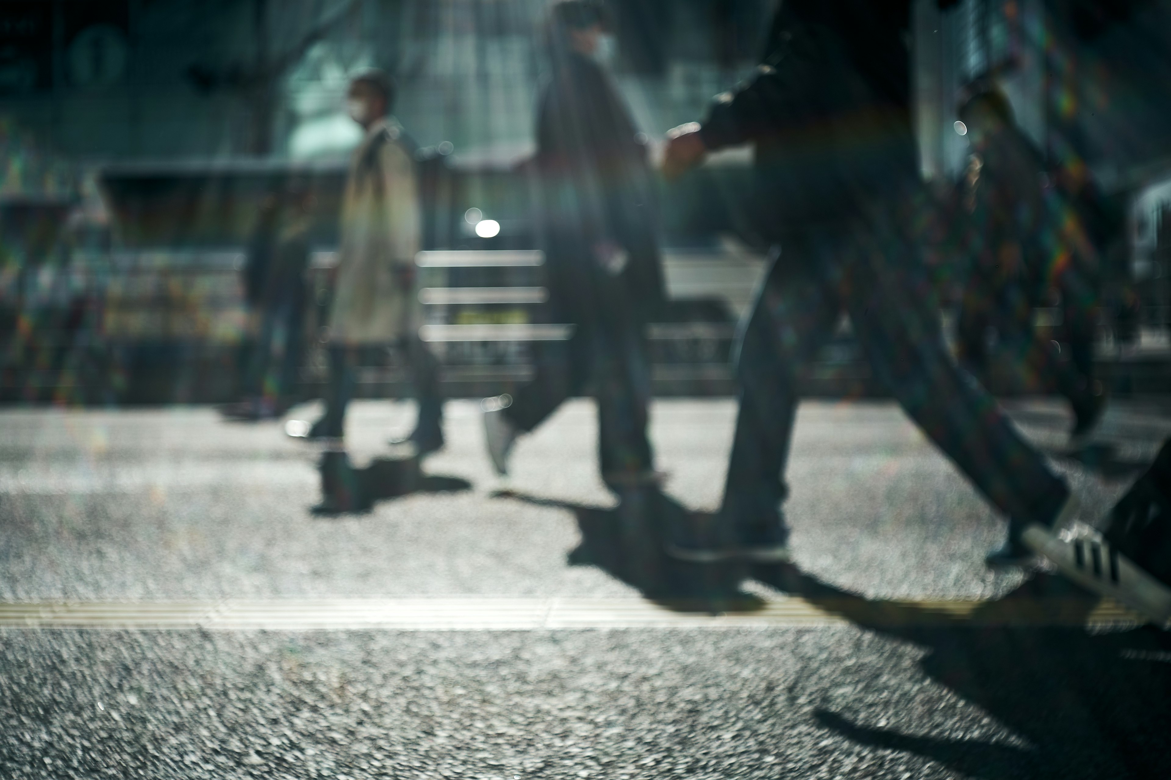 Silhouettes of people walking on a street in a blurred nighttime scene