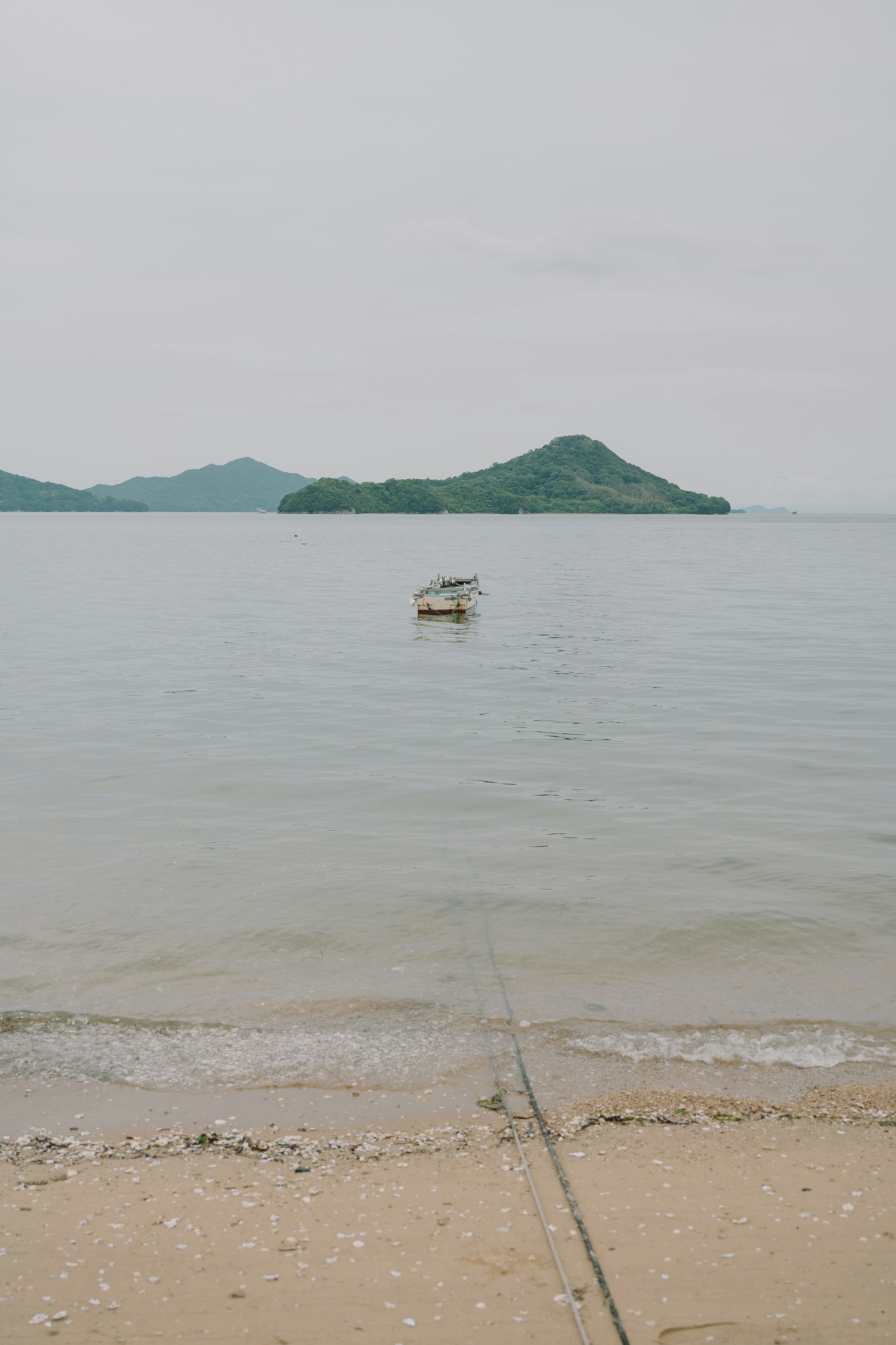 平靜的海面上有一隻小船，背景是島嶼