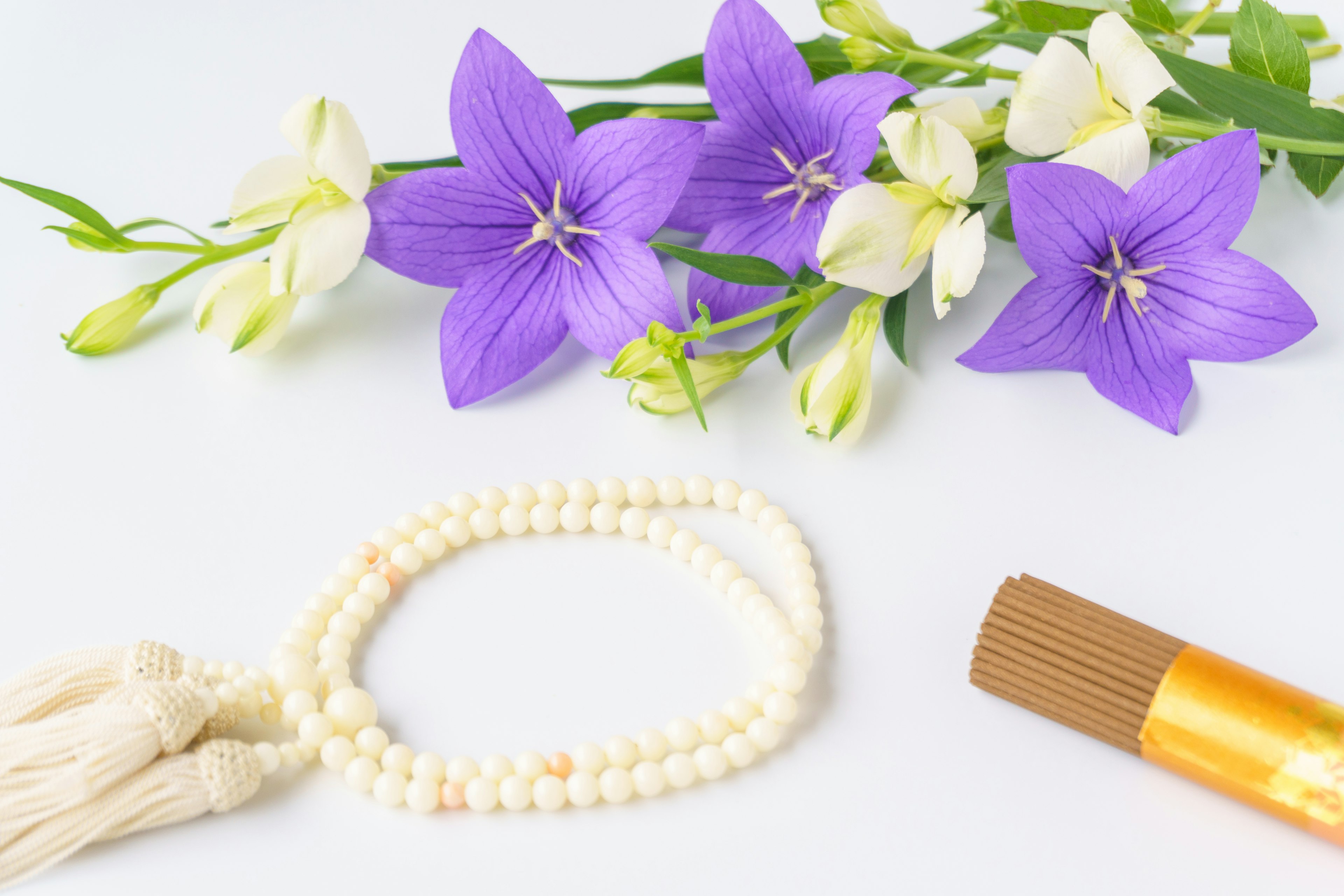 A serene arrangement featuring purple flowers and a white bead bracelet