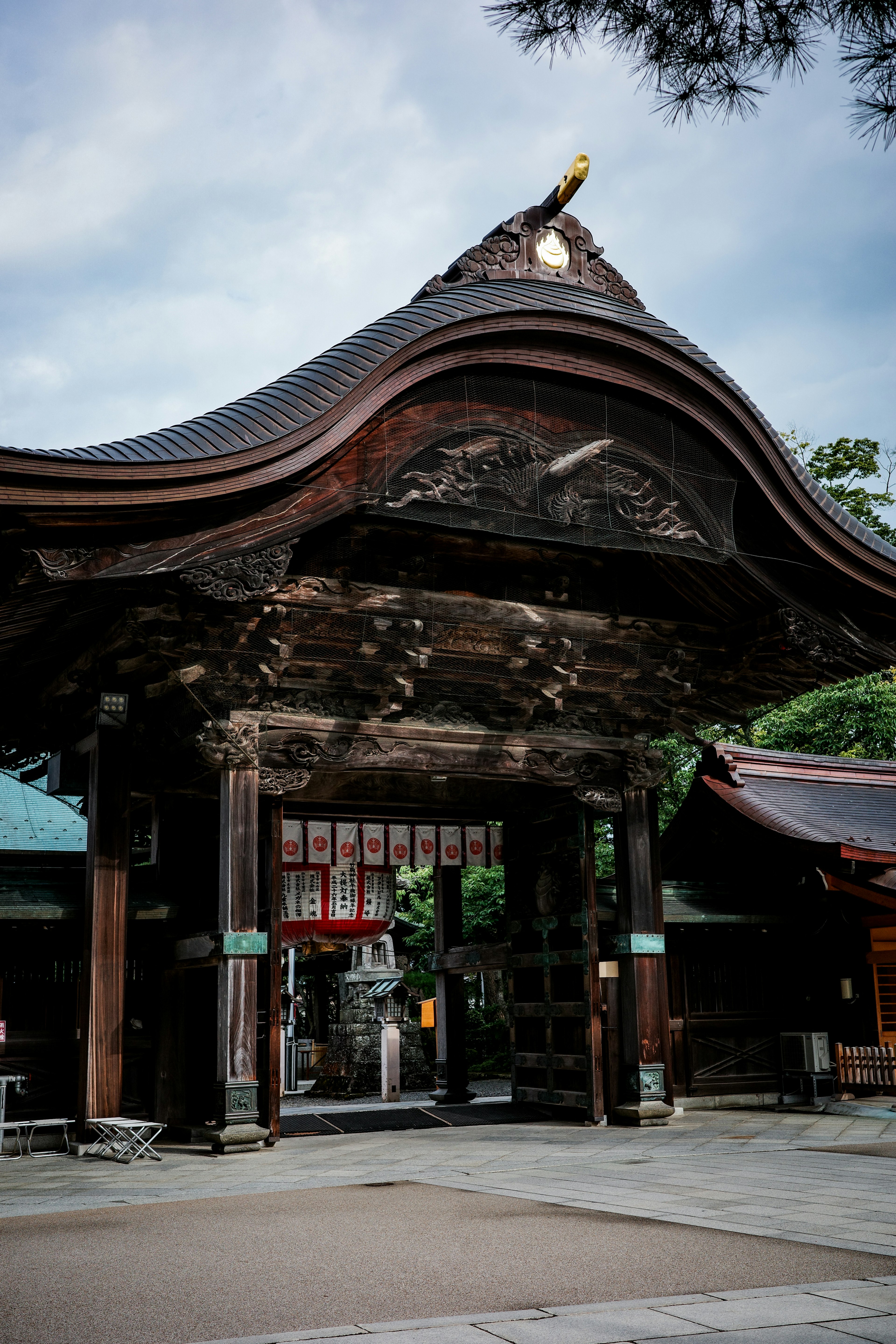 伝統的な木造の神社の門、彫刻と屋根のデザインが特徴